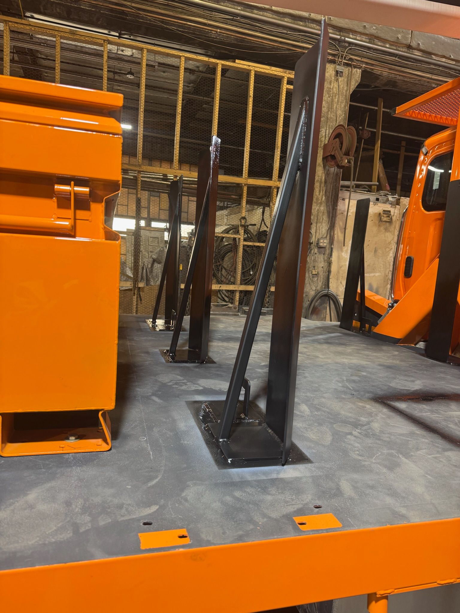 Orange industrial machinery in a factory, with black metal supports and pipes in the background.