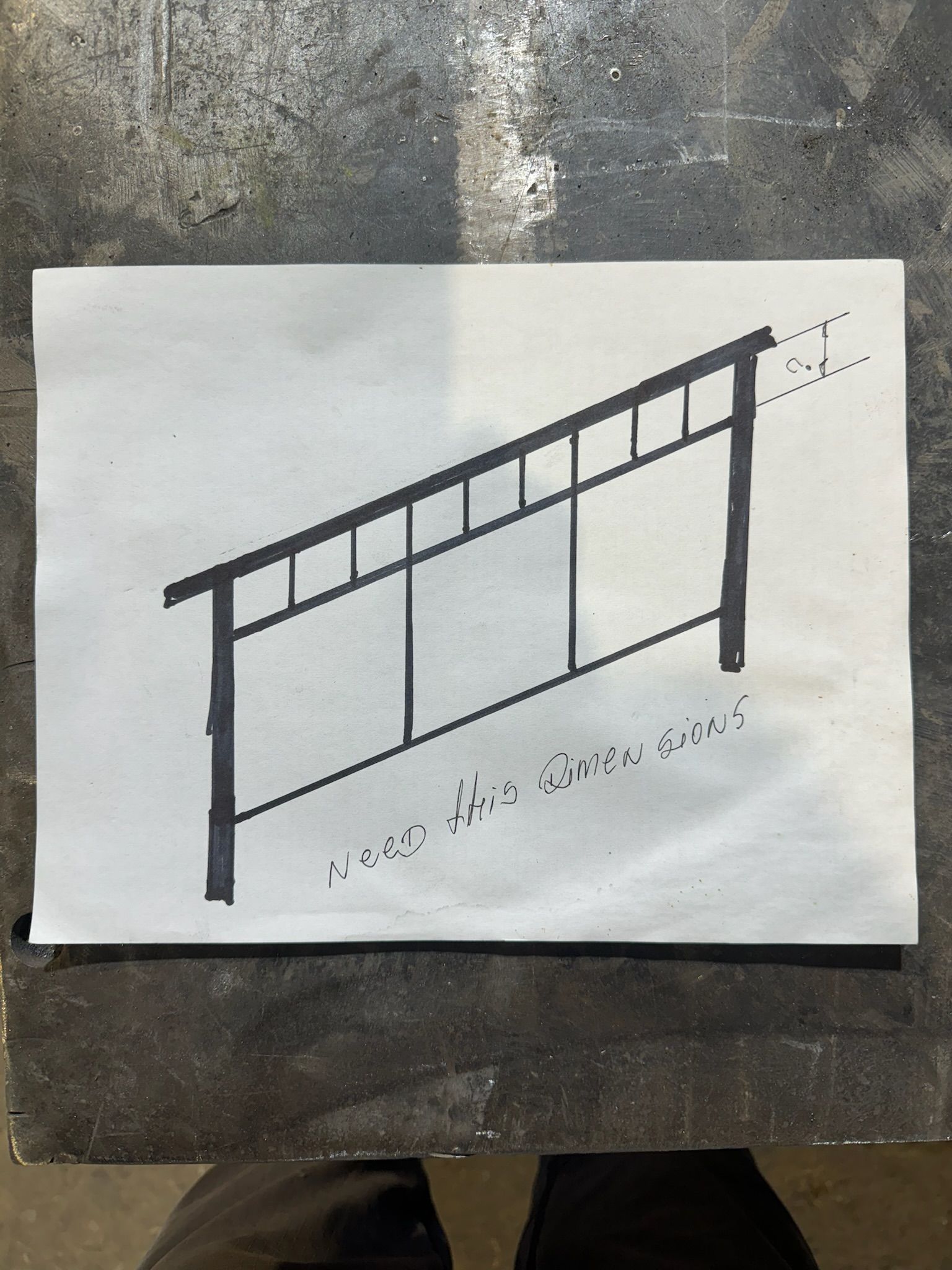 Sketch of an accessibility ramp with handrail and support posts on white paper over concrete.