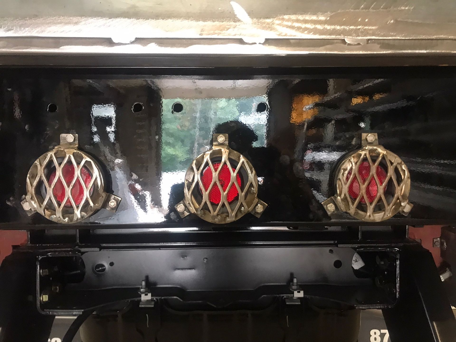 Three red-and-gold decorative crowns or medallions displayed on a black shelf