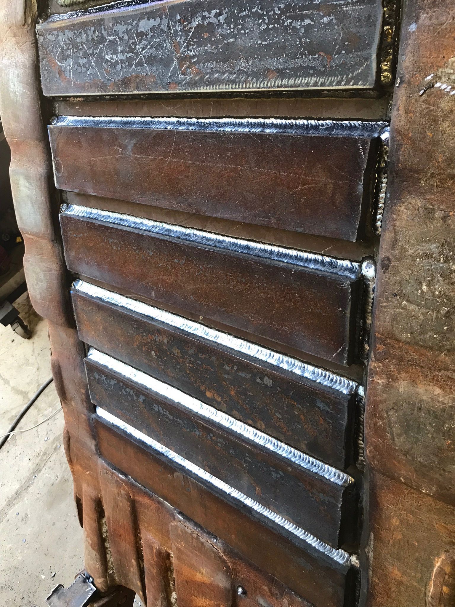 Rusty brown metal vent or louvered panel with horizontal slats outdoors