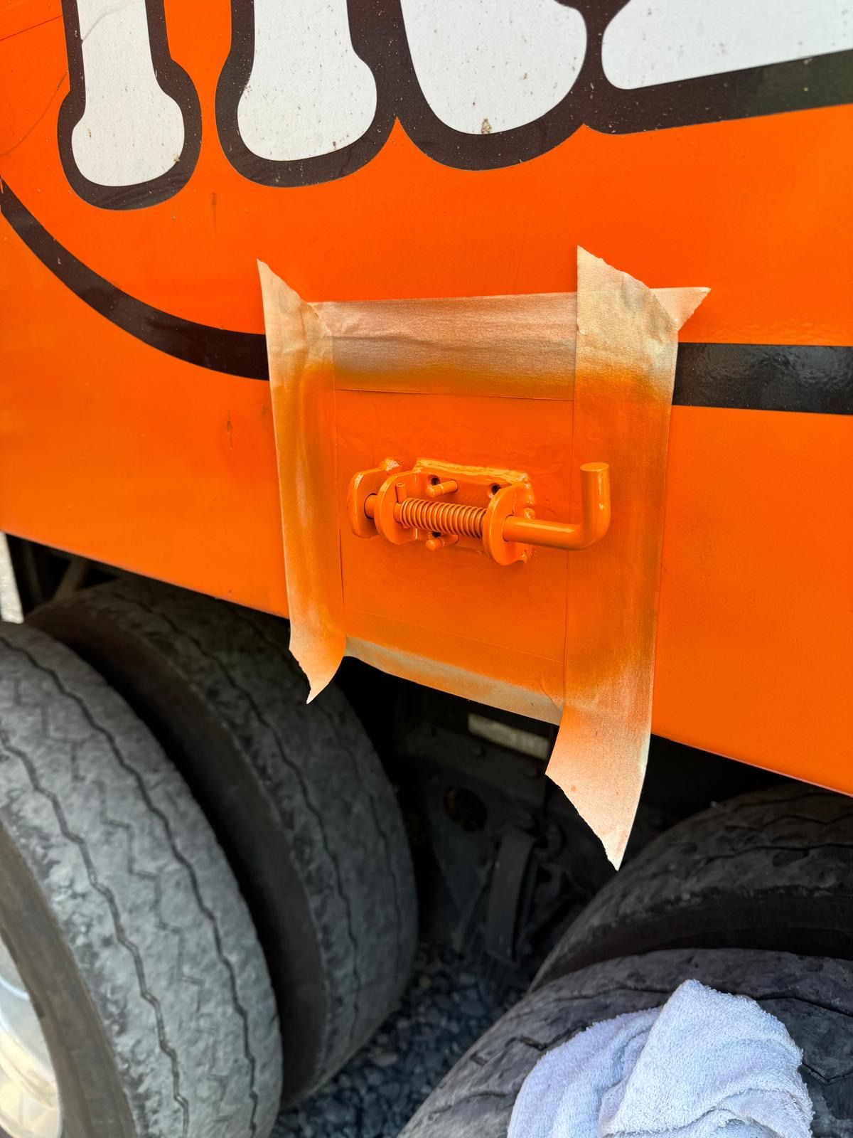 Orange vehicle side panel with a taped-over access latch above a tire