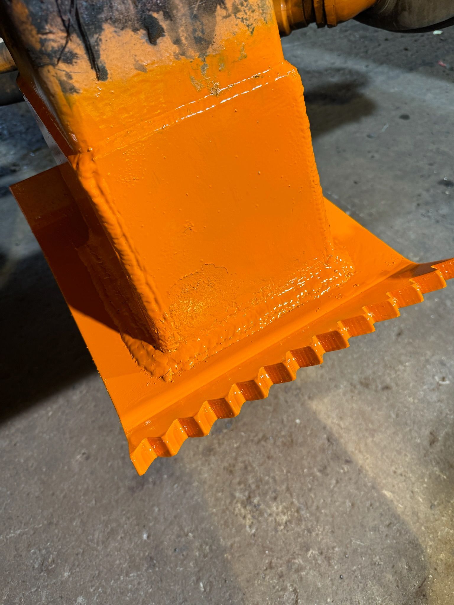 Orange industrial machine foot resting on a concrete floor