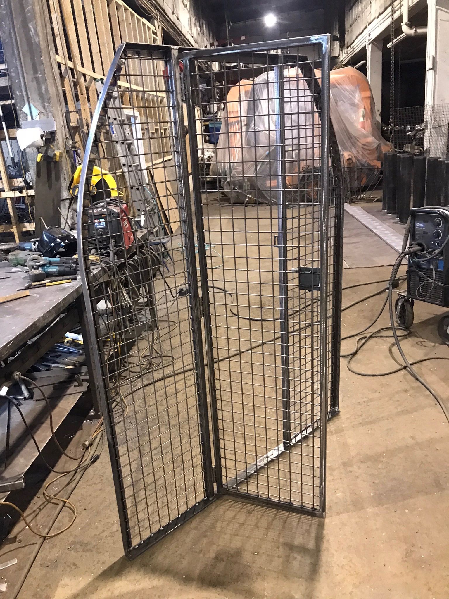 Metal stage prop panel with lattice pattern, leaning open in an industrial workshop or backstage area.