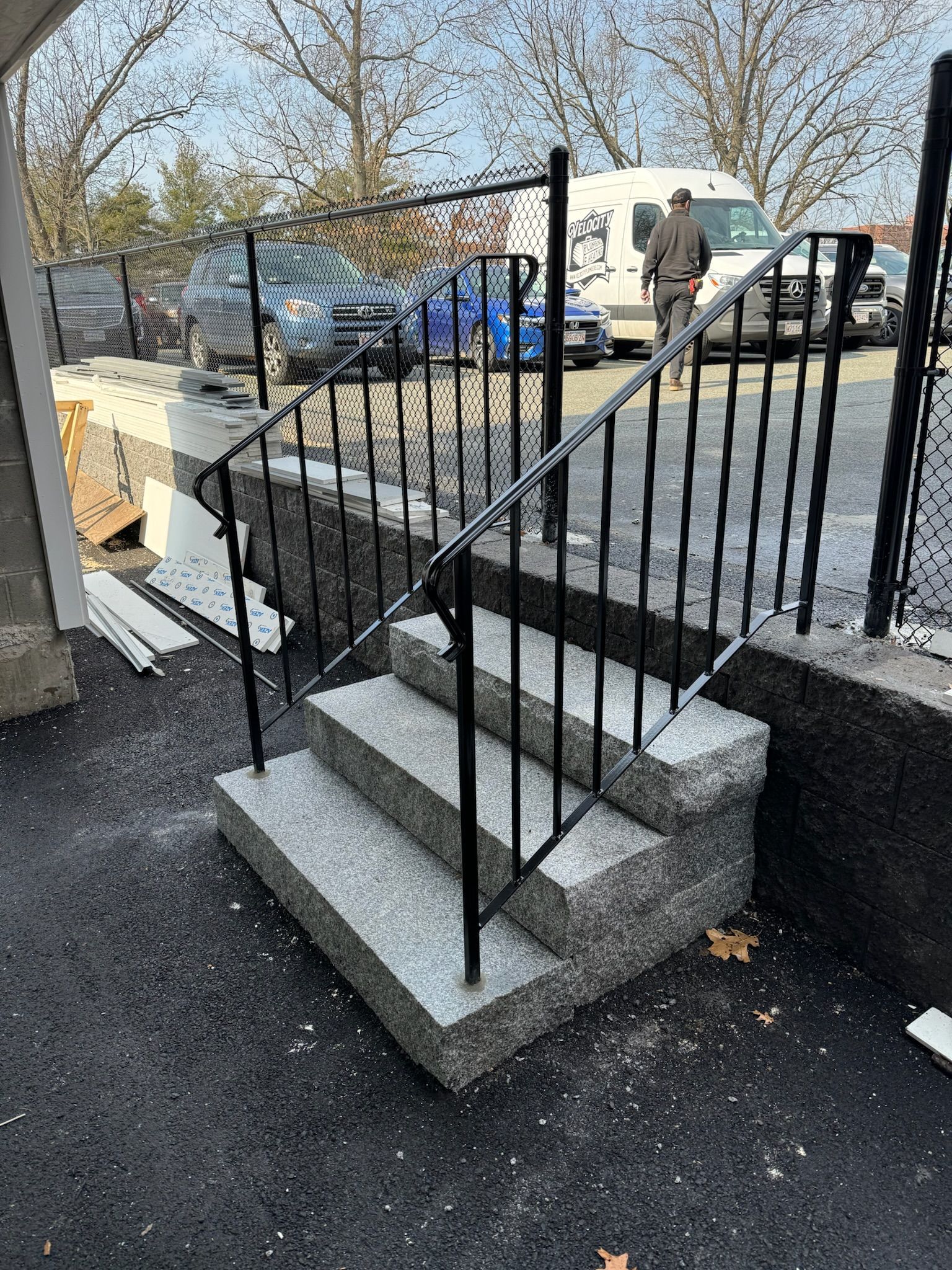 Concrete steps with black metal railings leading to a raised walkway outdoors.