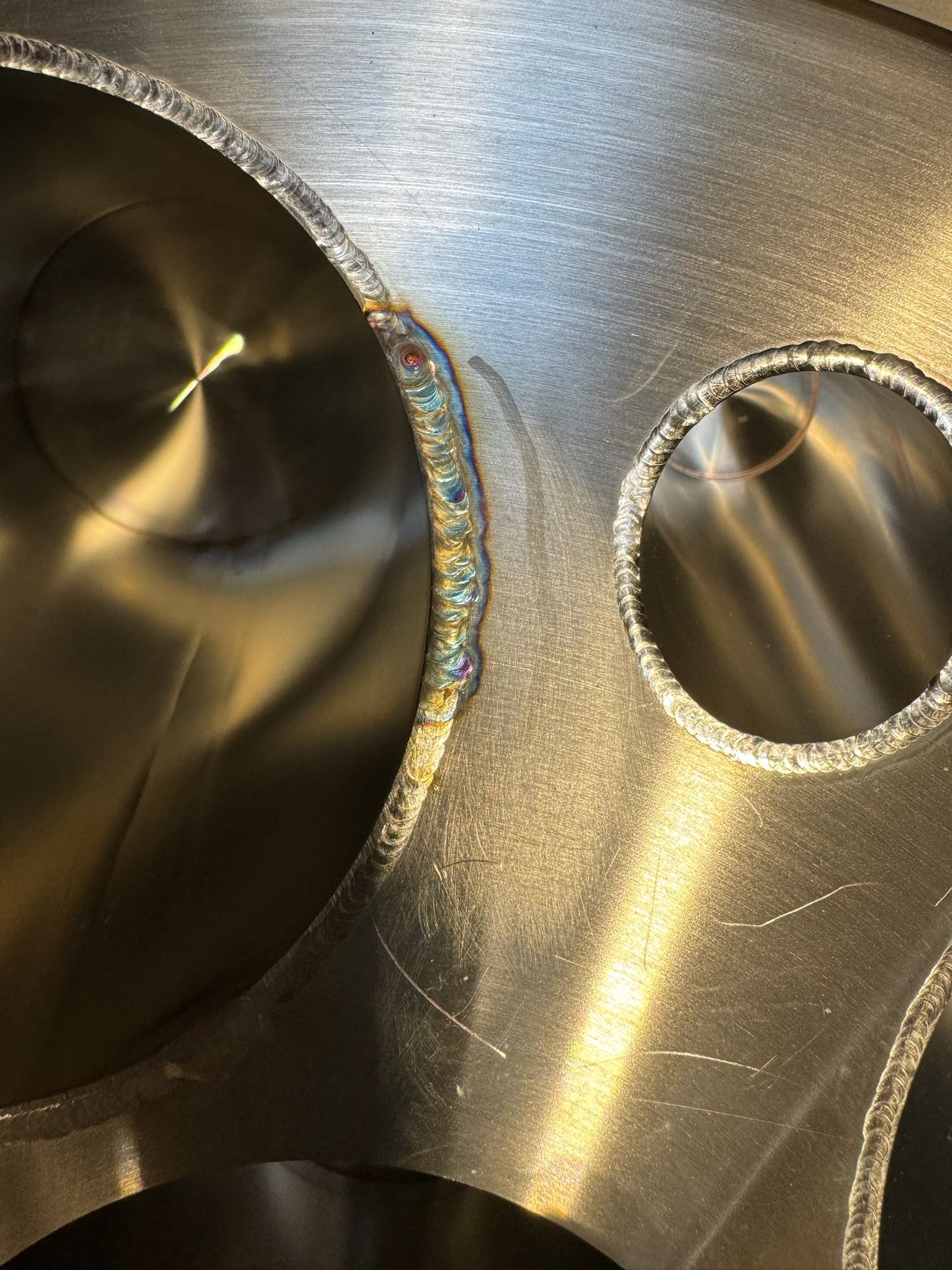 Close-up of polished metal with two circular machined holes and reflective brushed surfaces