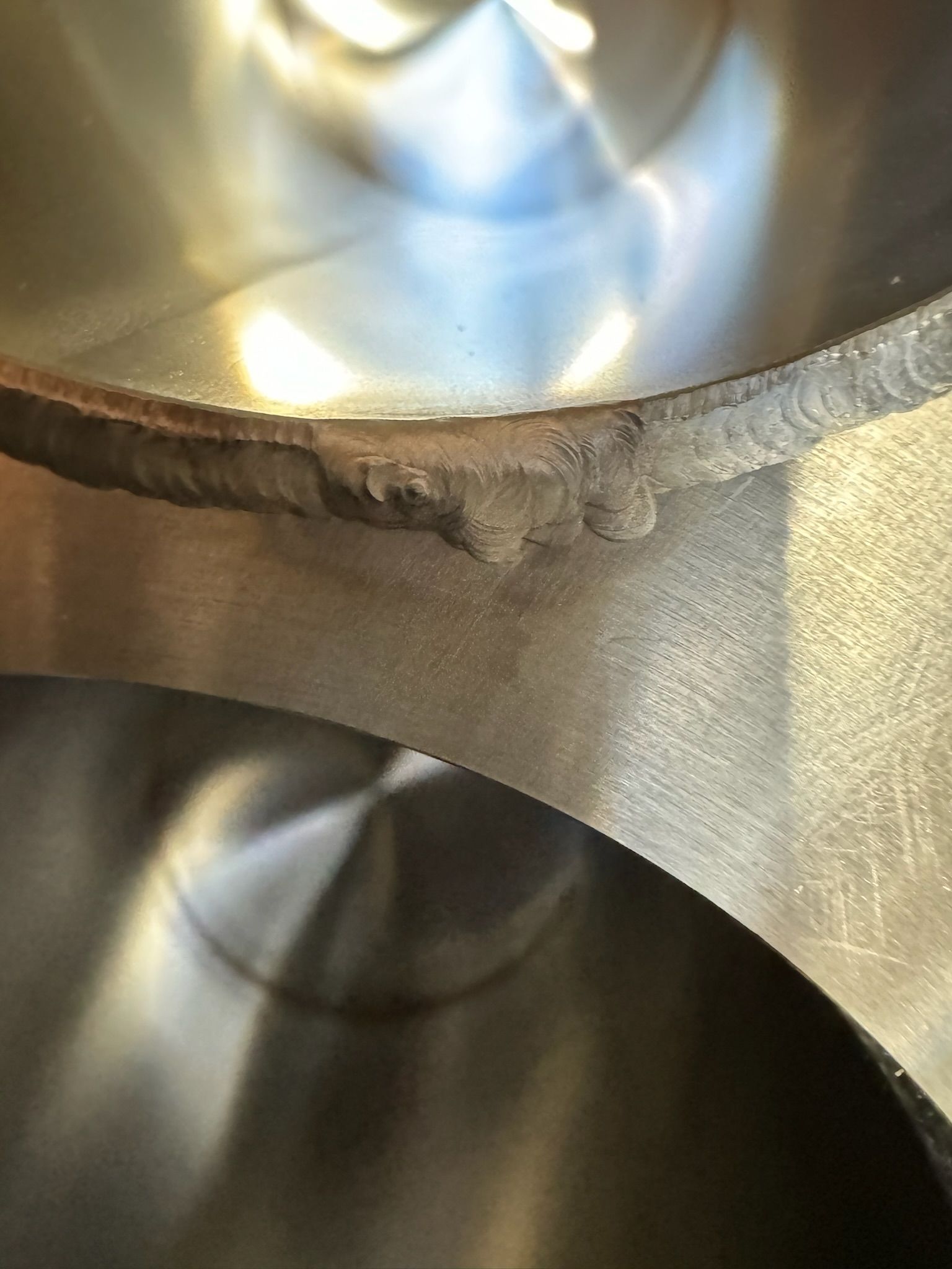 Close-up of a metal pipe interior with a rough welded seam and reflective silver surface