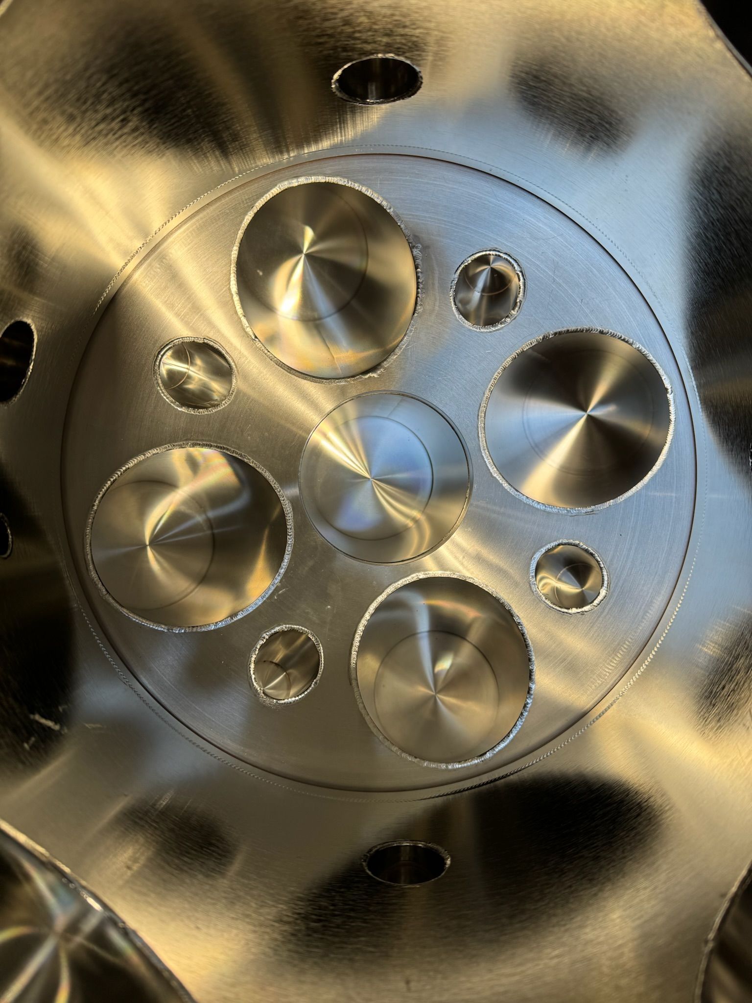 Close-up of a metallic machined circular part with polished discs and holes.