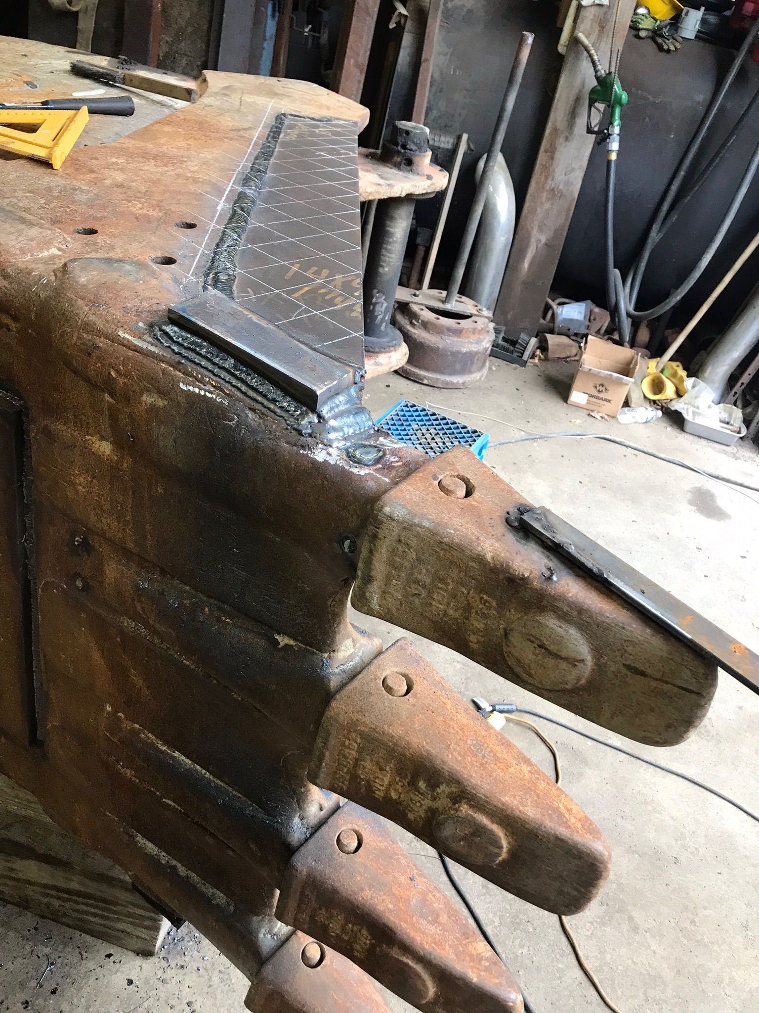 Rusty metal claw-like sculpture on a workbench in a cluttered workshop