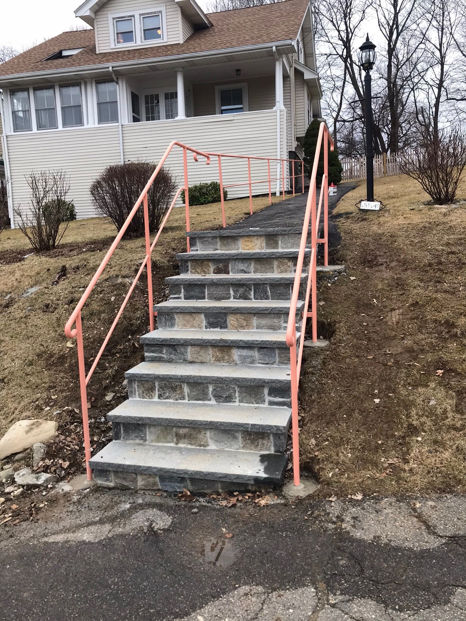 Outdoor staircase with pink handrails leading up a house on a hillside