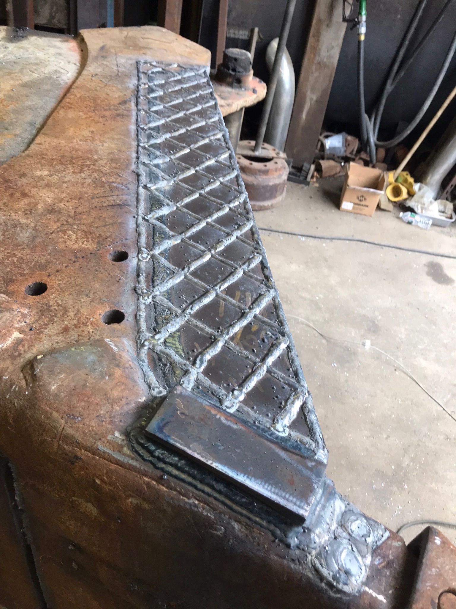 Diamond-plate metal strip welded onto a rusty workbench in a workshop