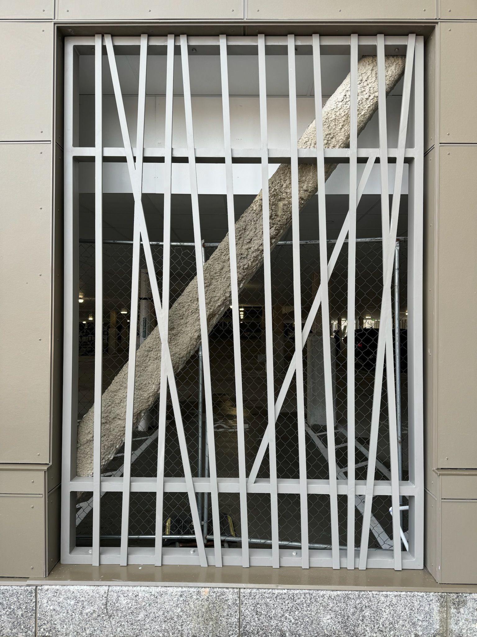 White barred window with crisscrossed broken blinds or tape over a dark interior opening