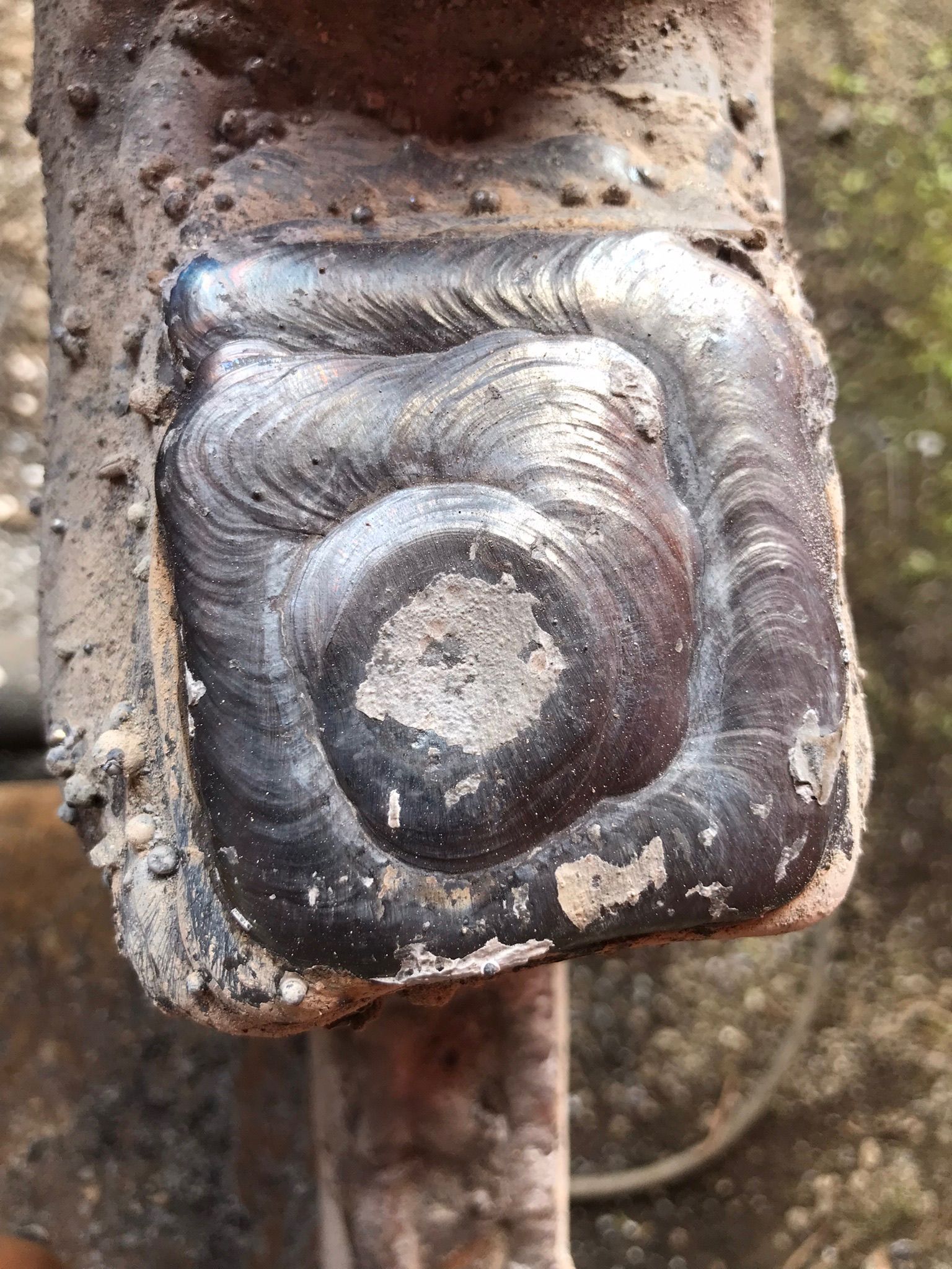 Close-up of a welded metal corner with a circular grind mark and rough, rusted surface.