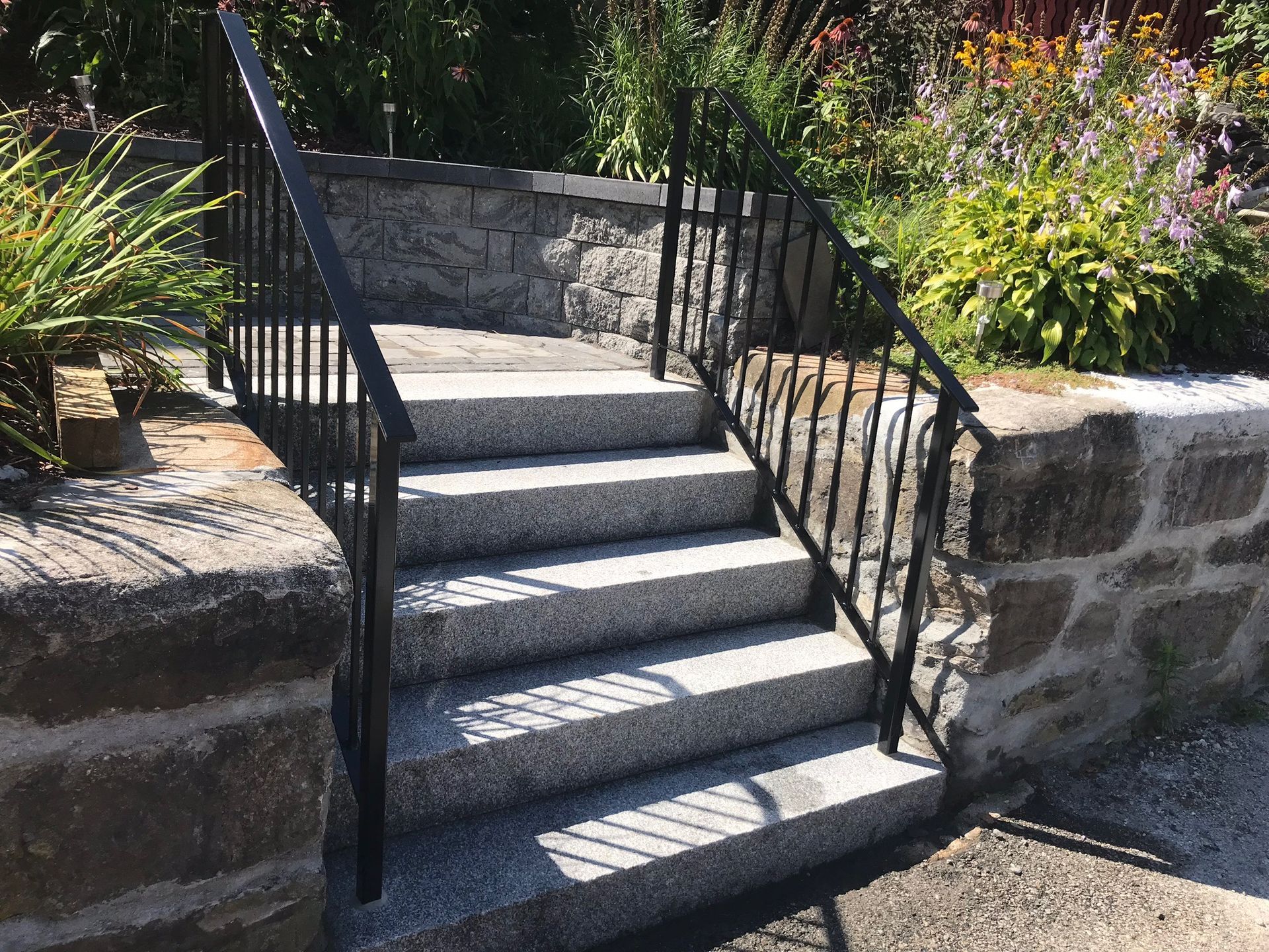 Stone steps with black metal railings leading up through a garden path