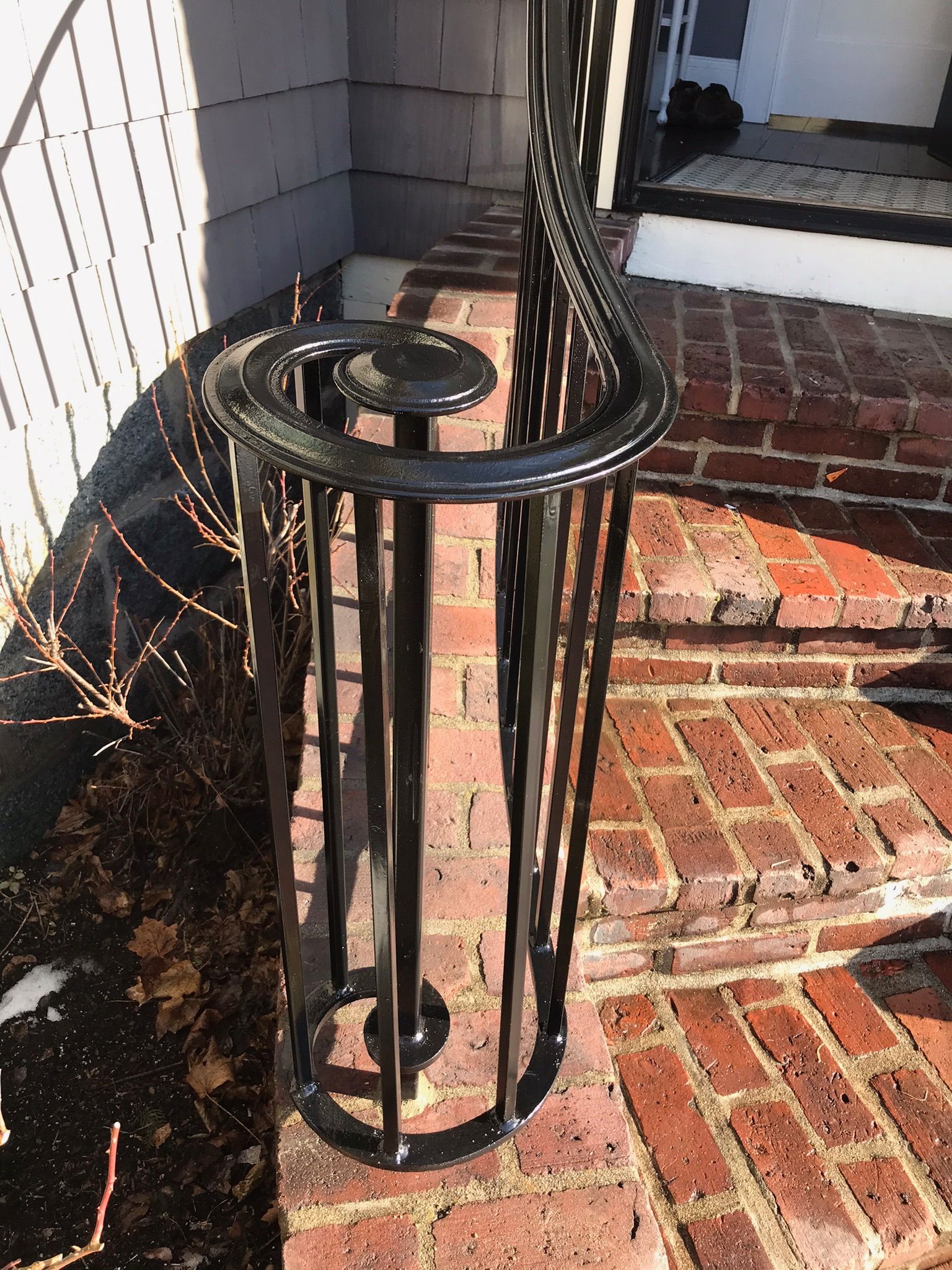 Black metal porch ashtray by brick steps on a front entry patio