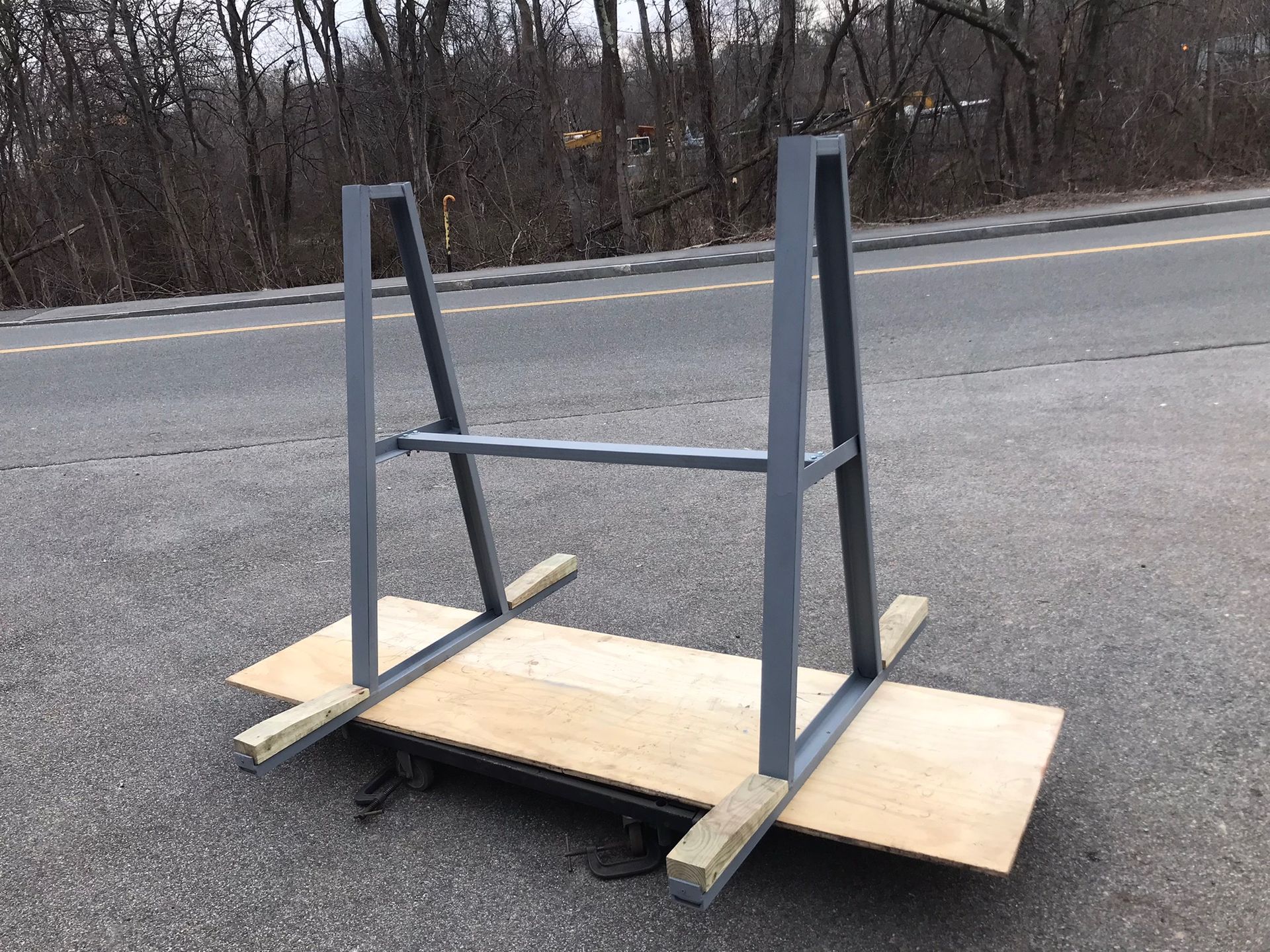 Homemade wooden and metal barrier on a roadside, mounted on a board base.