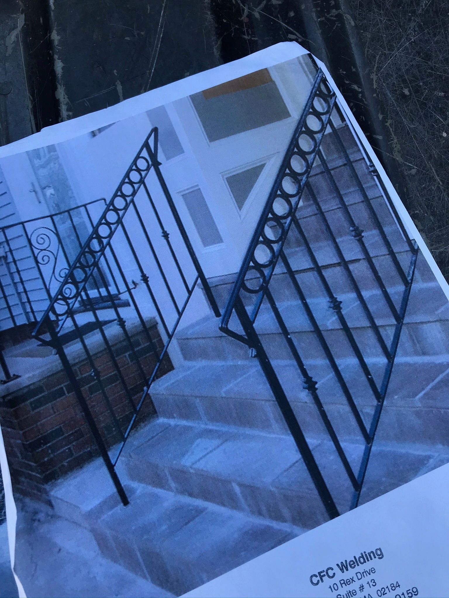 Snow-covered front steps with black railings leading to a house entrance