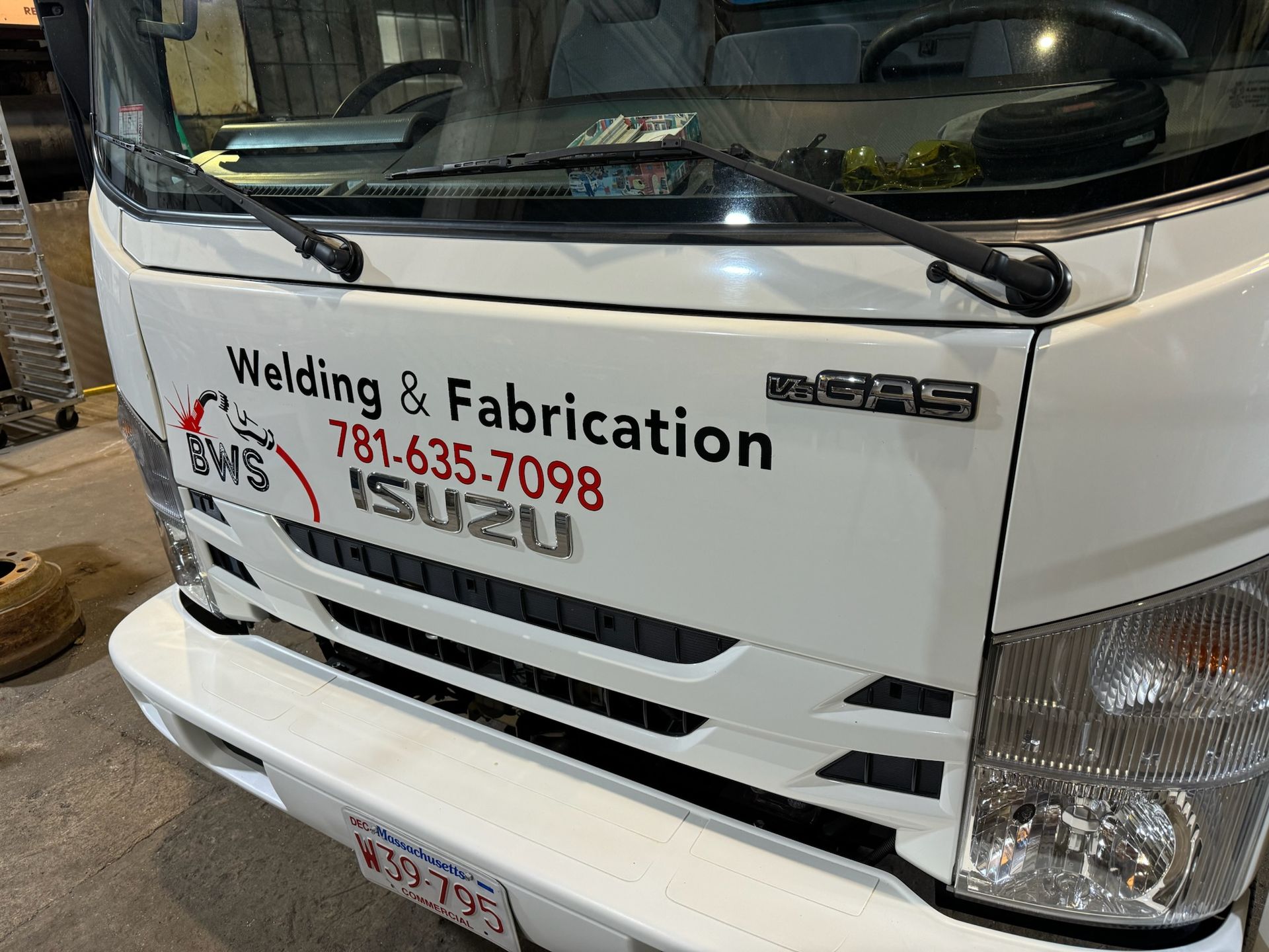 Close-up of a white Isuzu truck front with Welding & Fabrication business lettering on the door