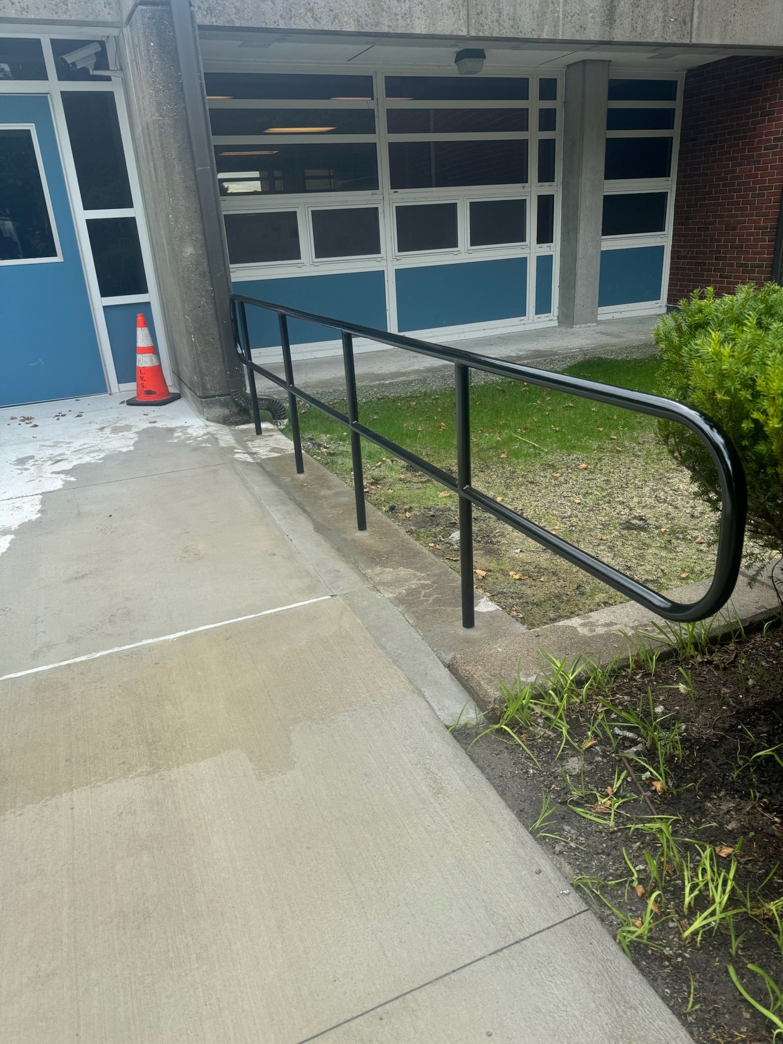 Accessible ramp with black handrails leading to a building entrance beside a garage door