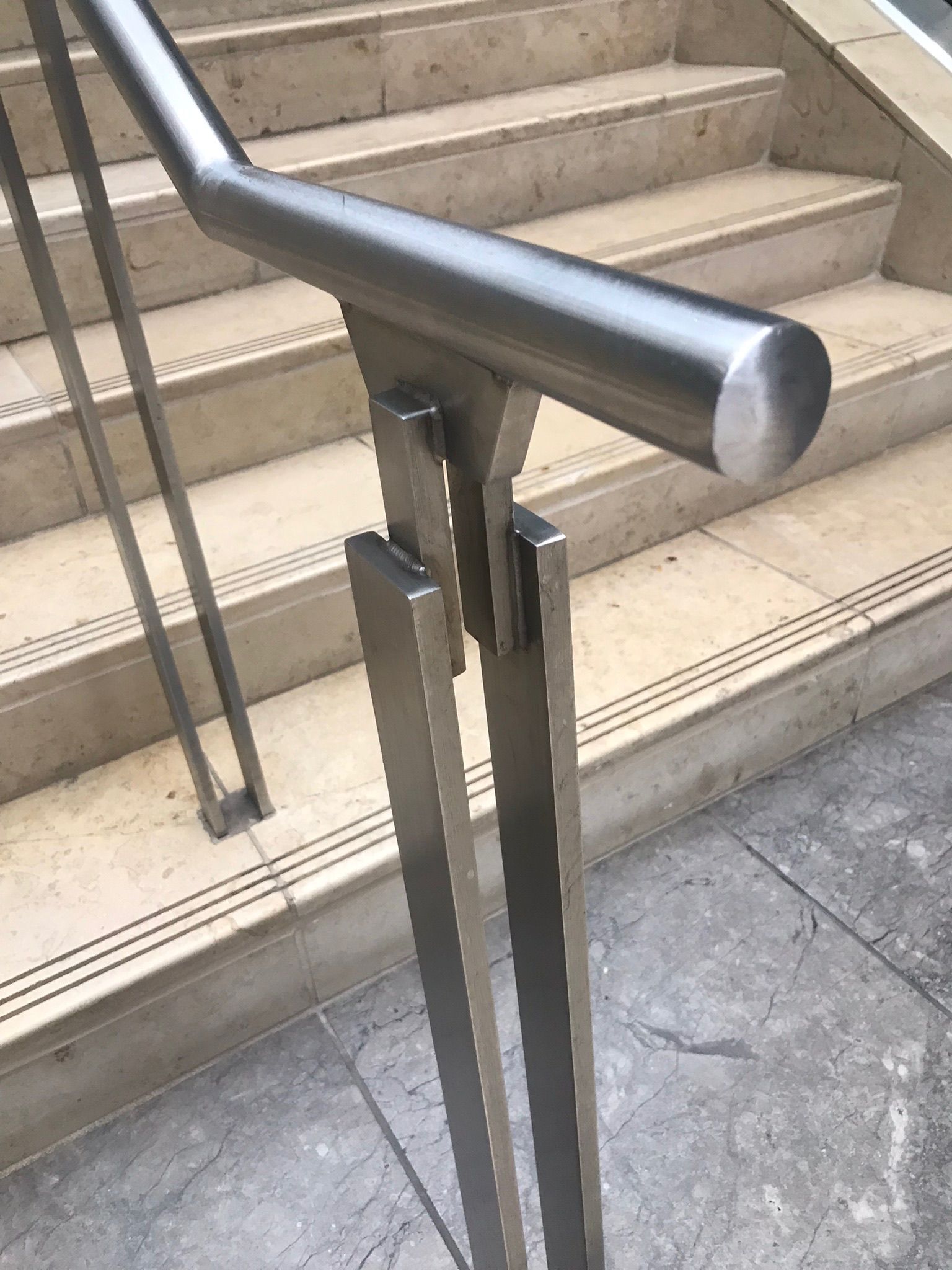 Metal handrail at the bottom of outdoor steps on a concrete walkway
