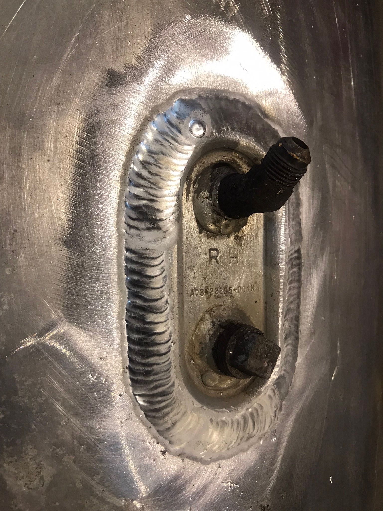 Close-up of a damaged metal socket with two protruding black bolts and a scratched silver surface