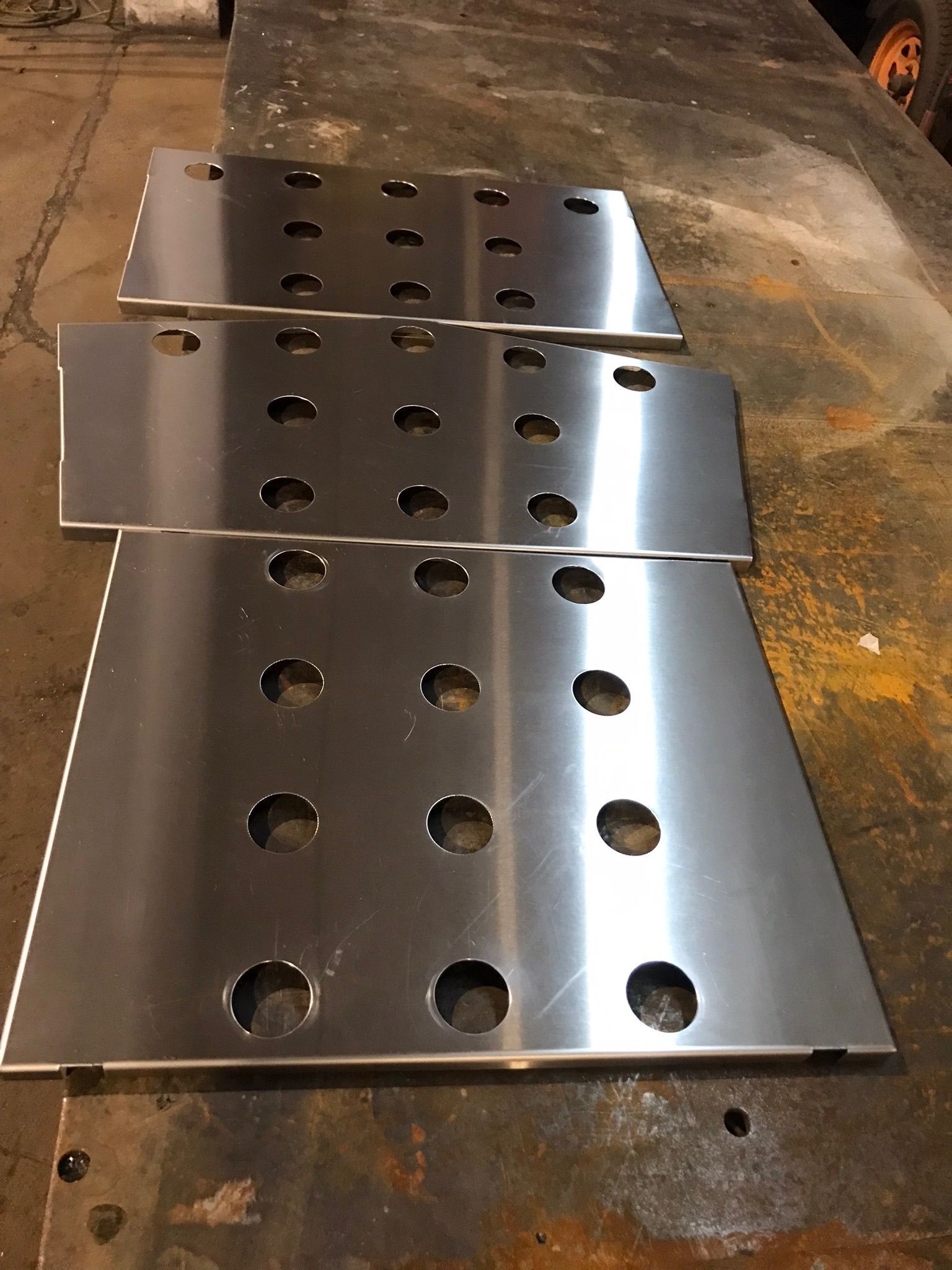 Perforated metal sheet with rows of circular holes on a workshop floor