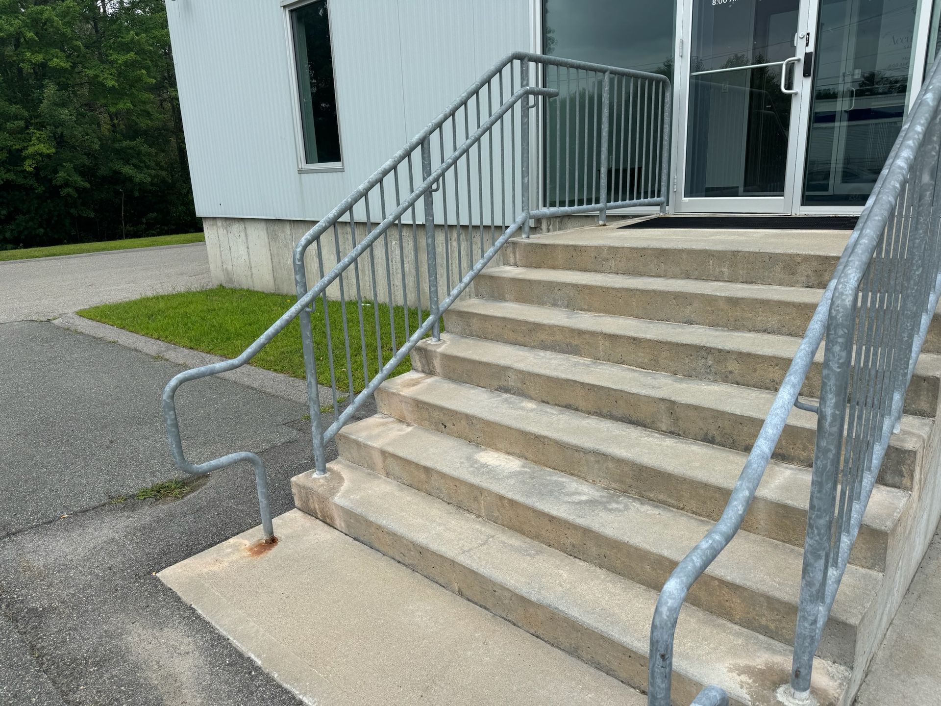 Concrete stairs with metal railings leading to a building entrance outside.