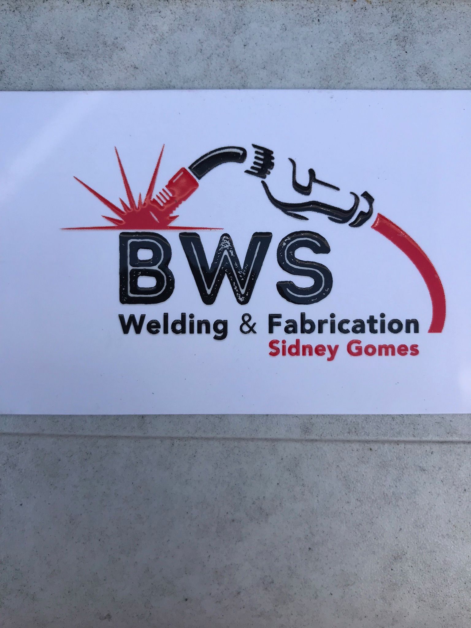 BWS Welding & Fabrication logo with red welding graphic and black text on a white sign