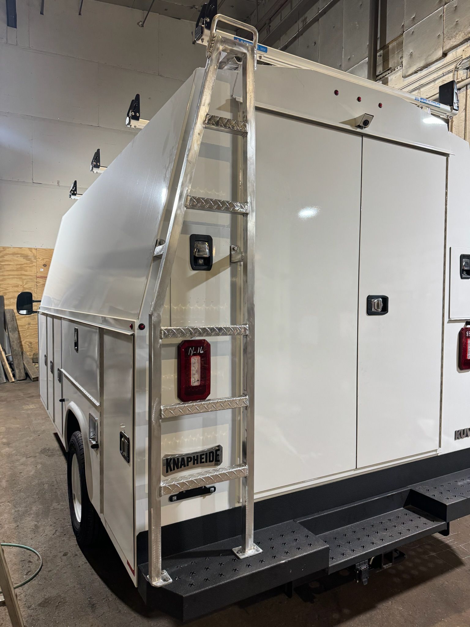White industrial trailer or generator unit with ladder and platform inside a warehouse