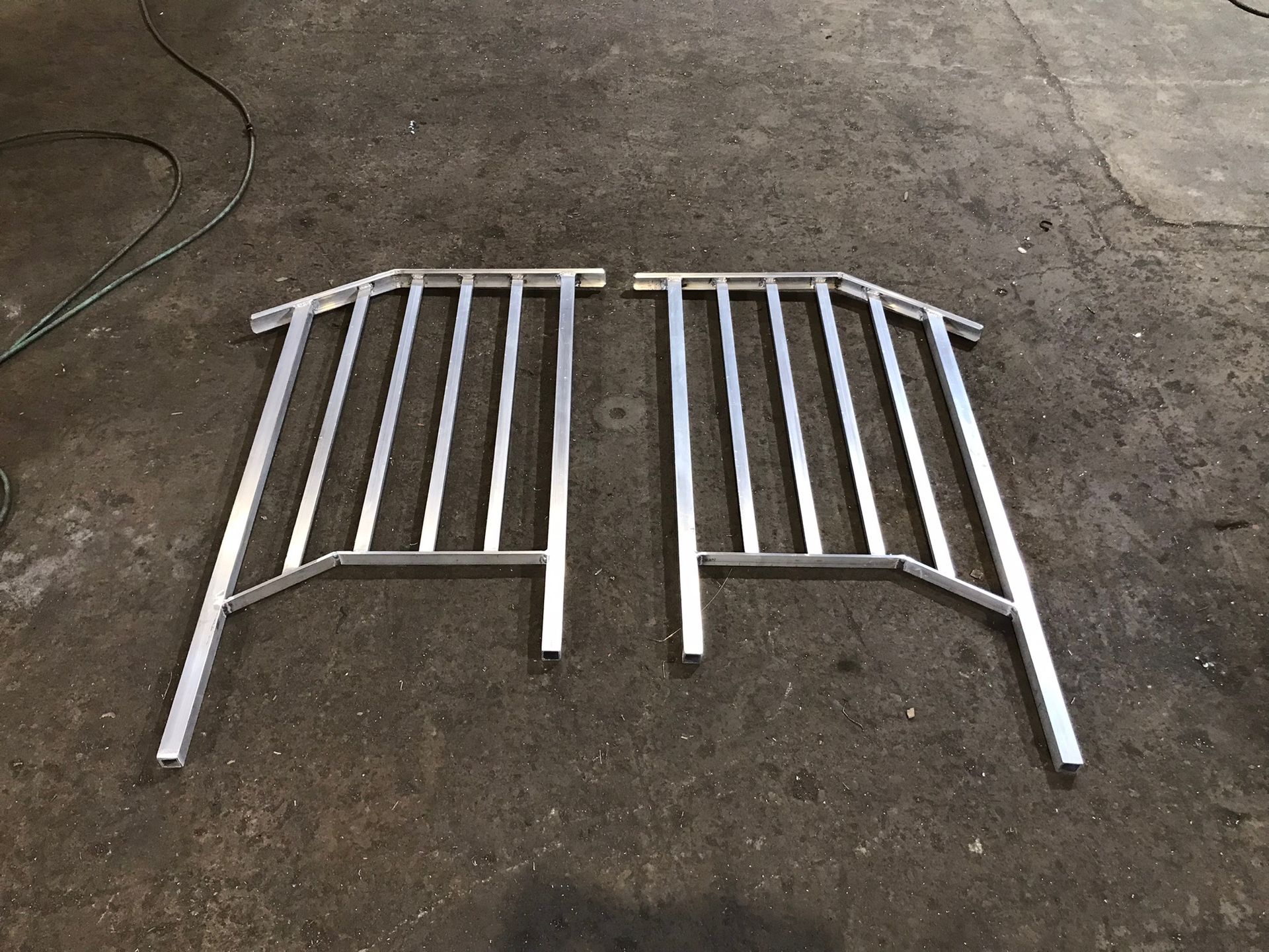 Two silver metal gate panels lying on a concrete floor