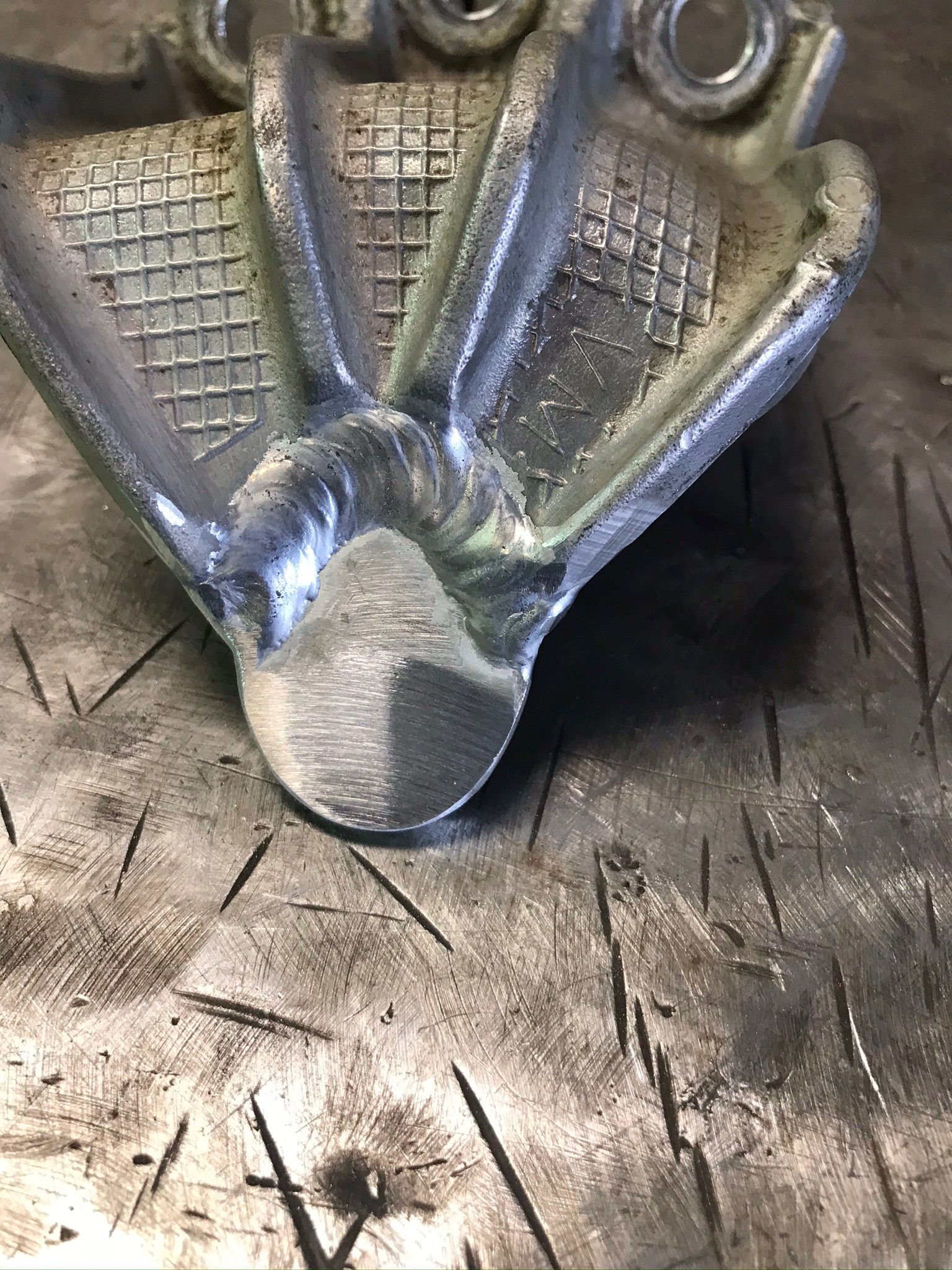 Metallic insect-shaped pendant with textured wings on a scratched surface
