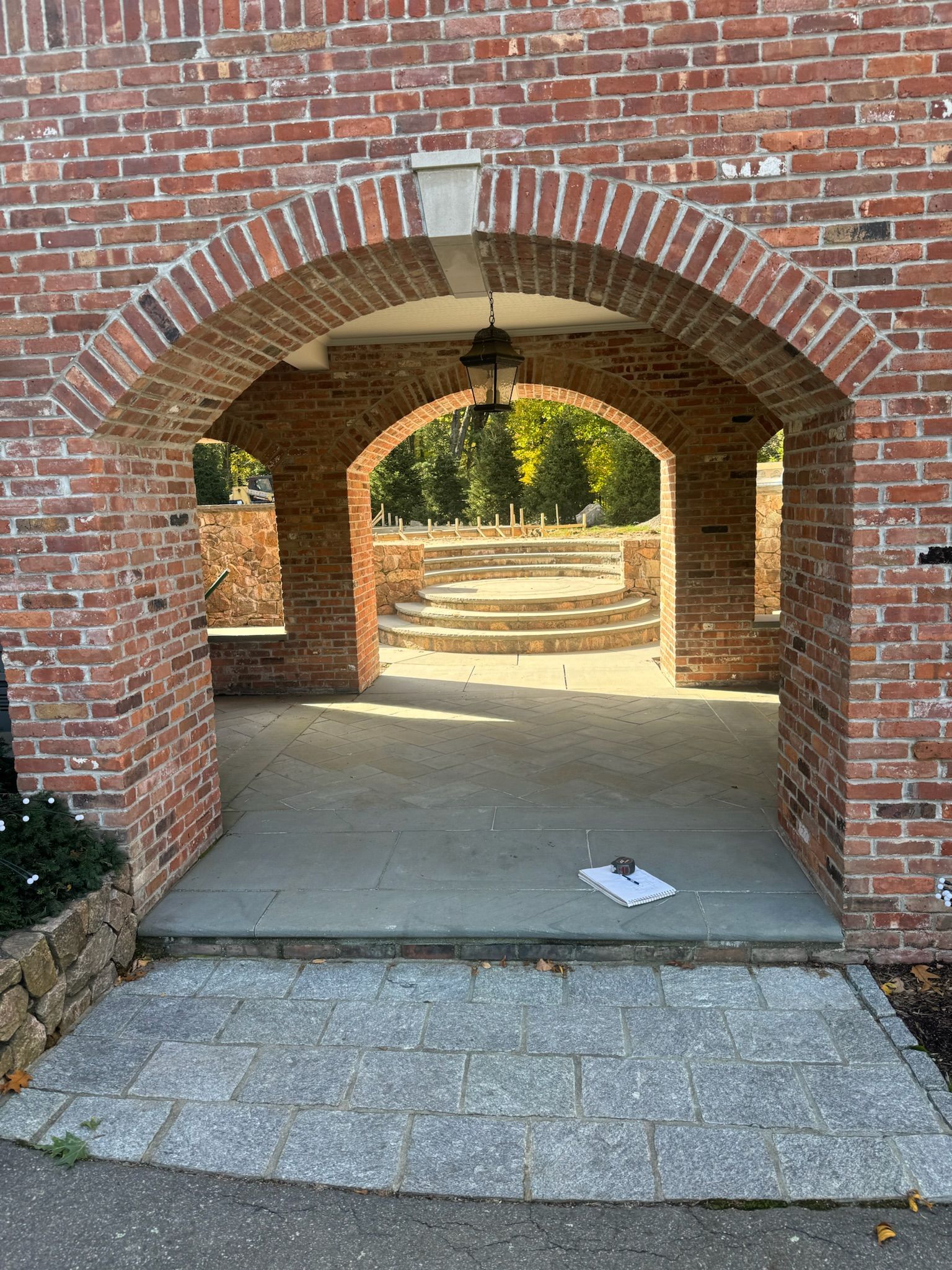 Brick archway walkway leading to a courtyard with stone steps and a hanging lantern