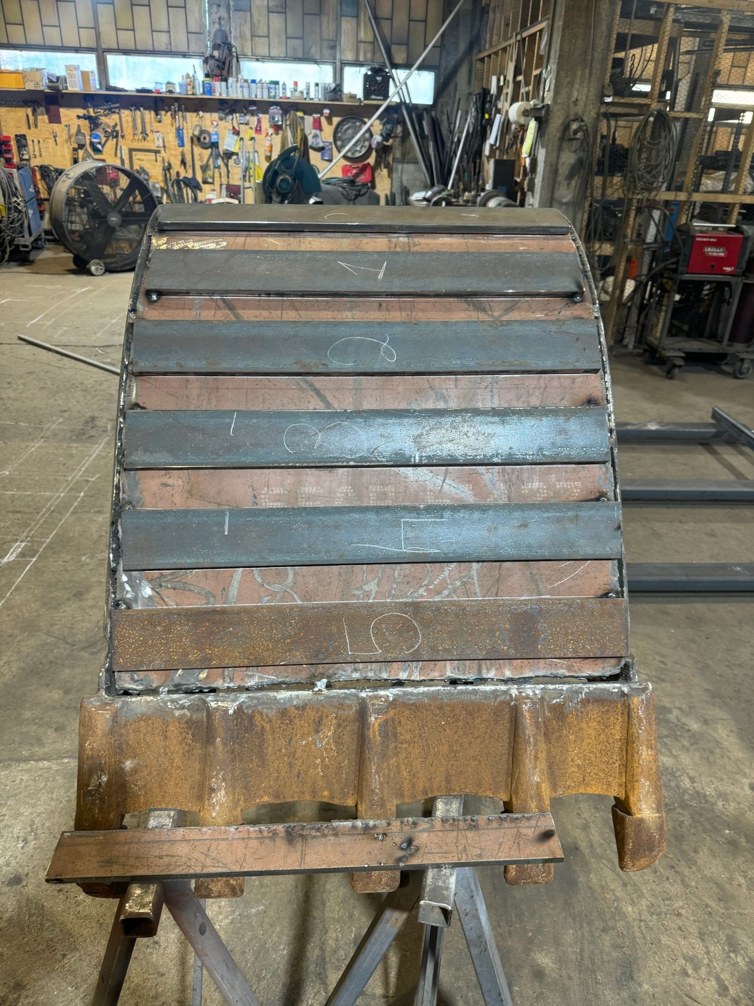 Rusty metal industrial machine part with ribbed slats in a workshop setting