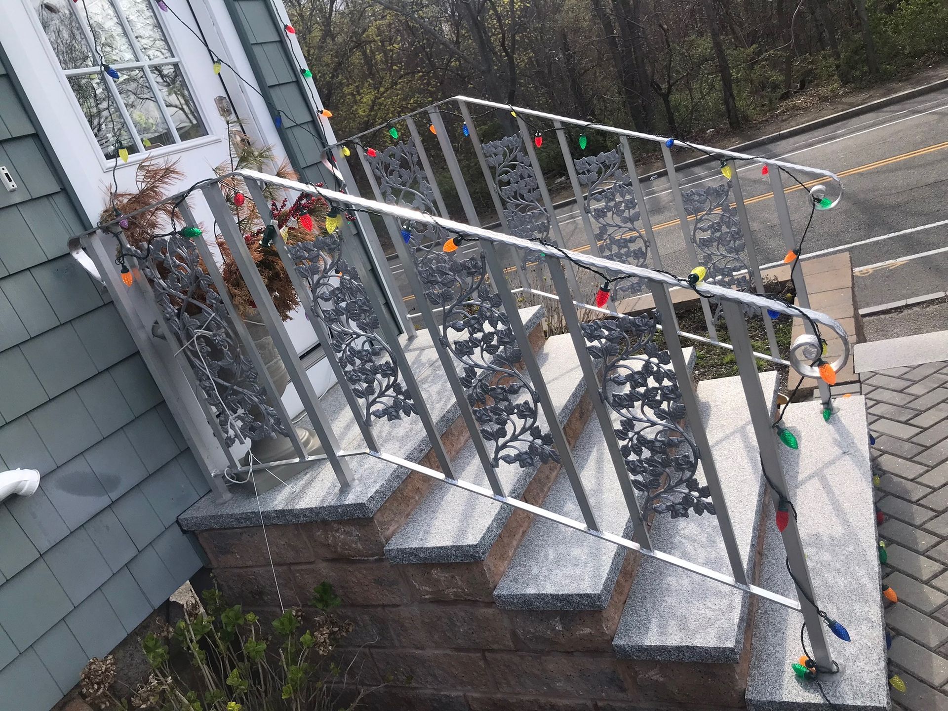 Outdoor staircase with metal railings and hanging string lights beside a gray house