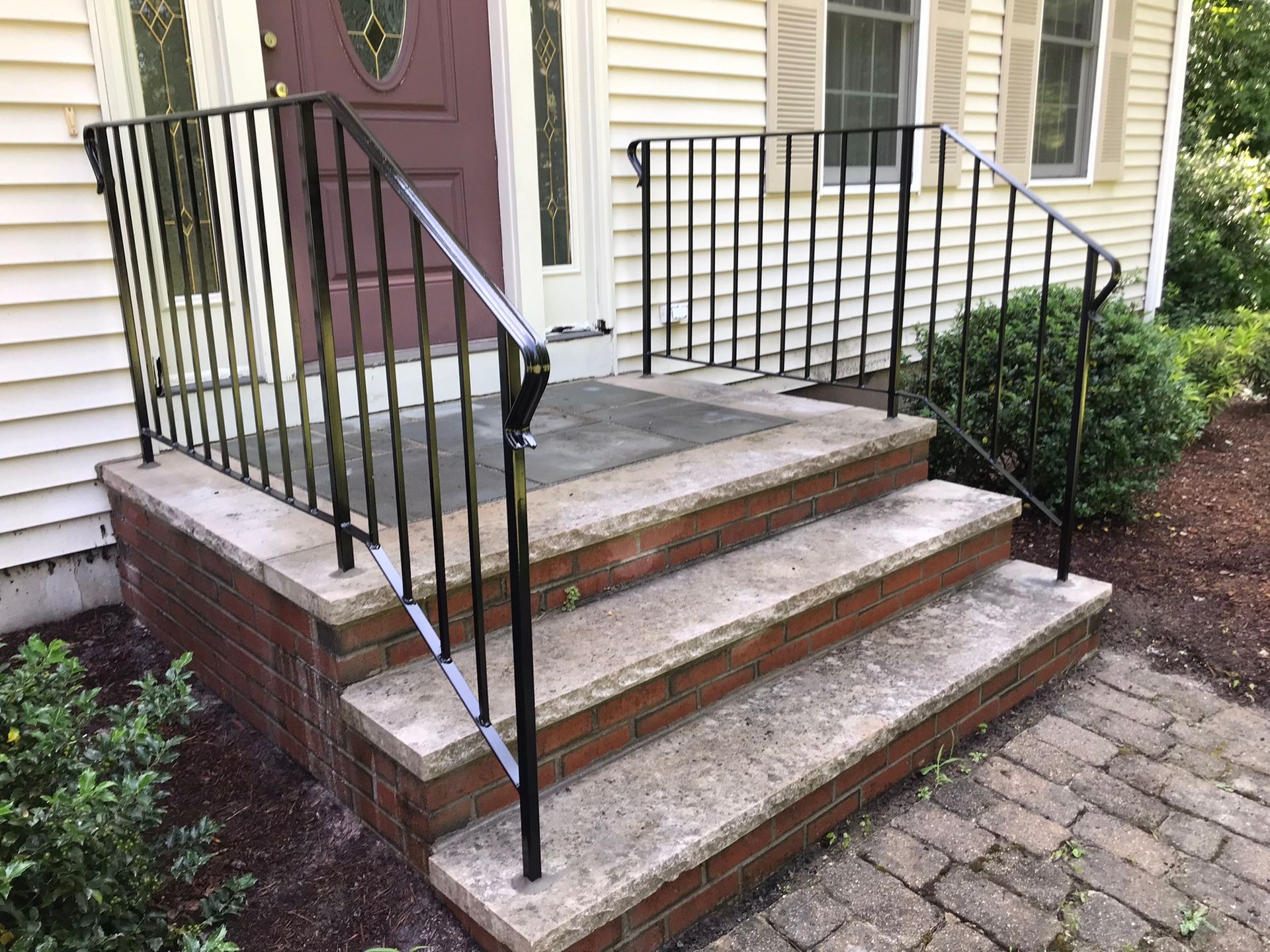 Brick front steps with black railings leading to a house entrance