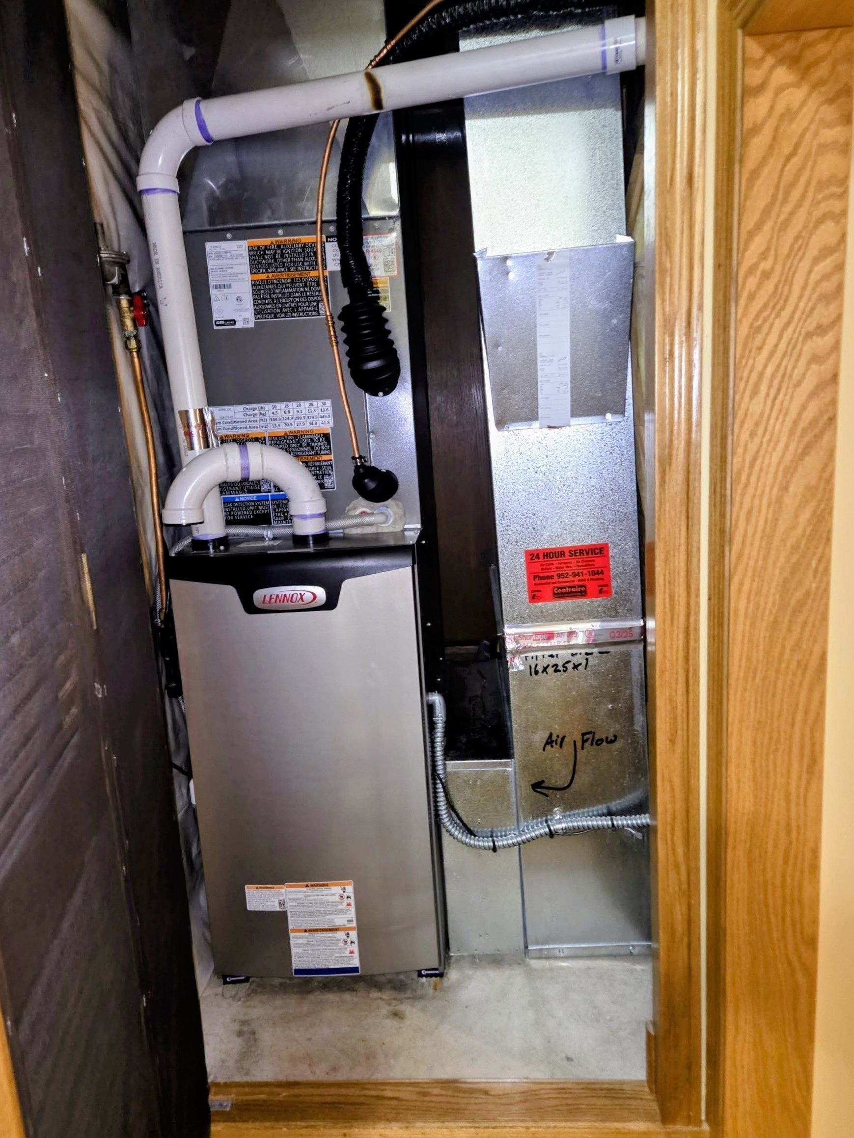 Utility closet with furnace, exposed ductwork, and PVC pipes inside unfinished wood framing.