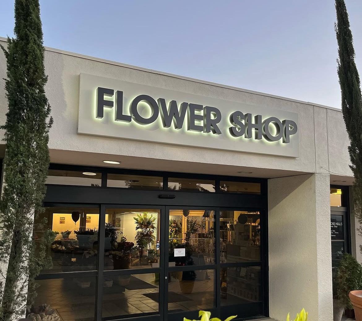 Flower shop storefront with illuminated sign and glass entrance at dusk