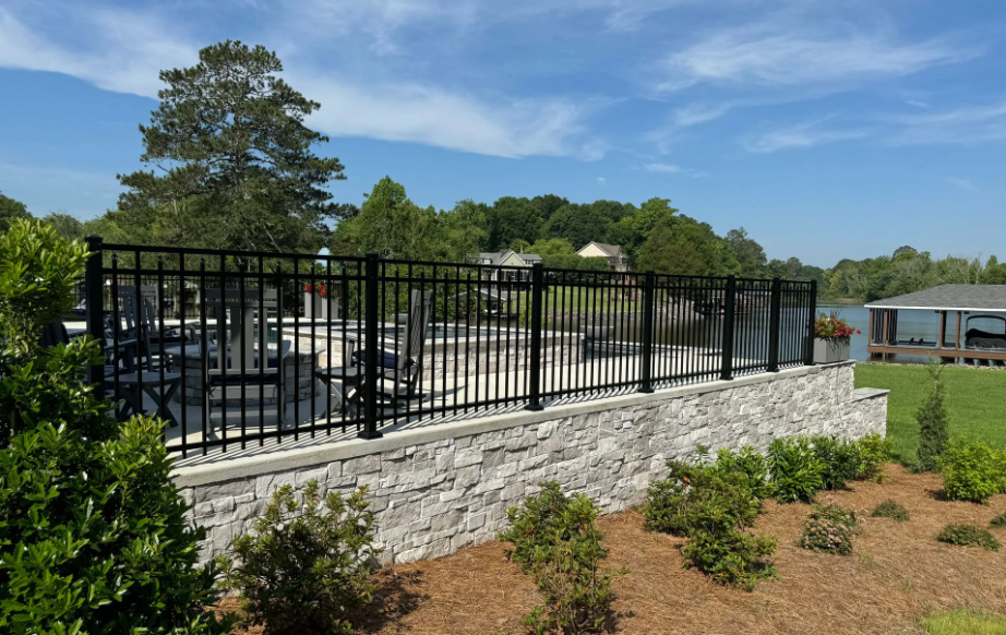 Poolside scene with blue water, lounge chairs, and rose bushes behind a fence.