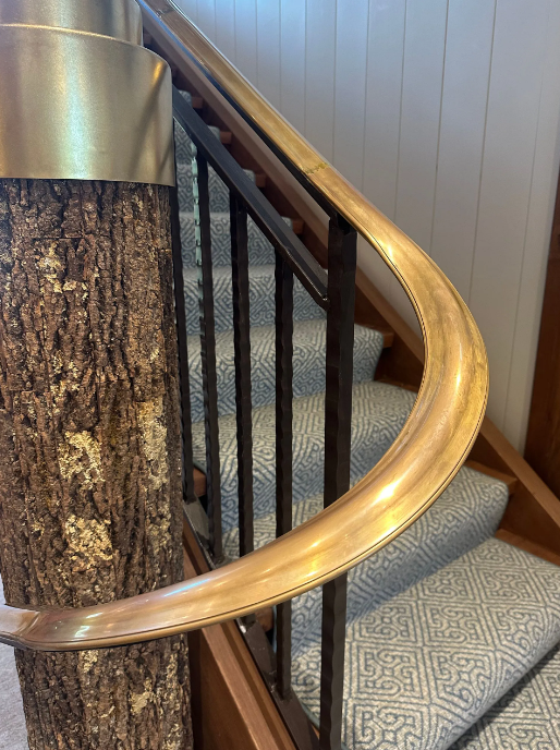 Ornate black iron railing with a stone staircase and tan walls.