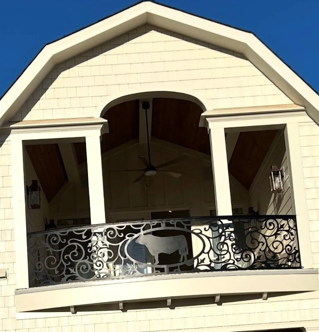 Black metal railing with rounded handrail, decorative post, and vertical bars, stairs in background.