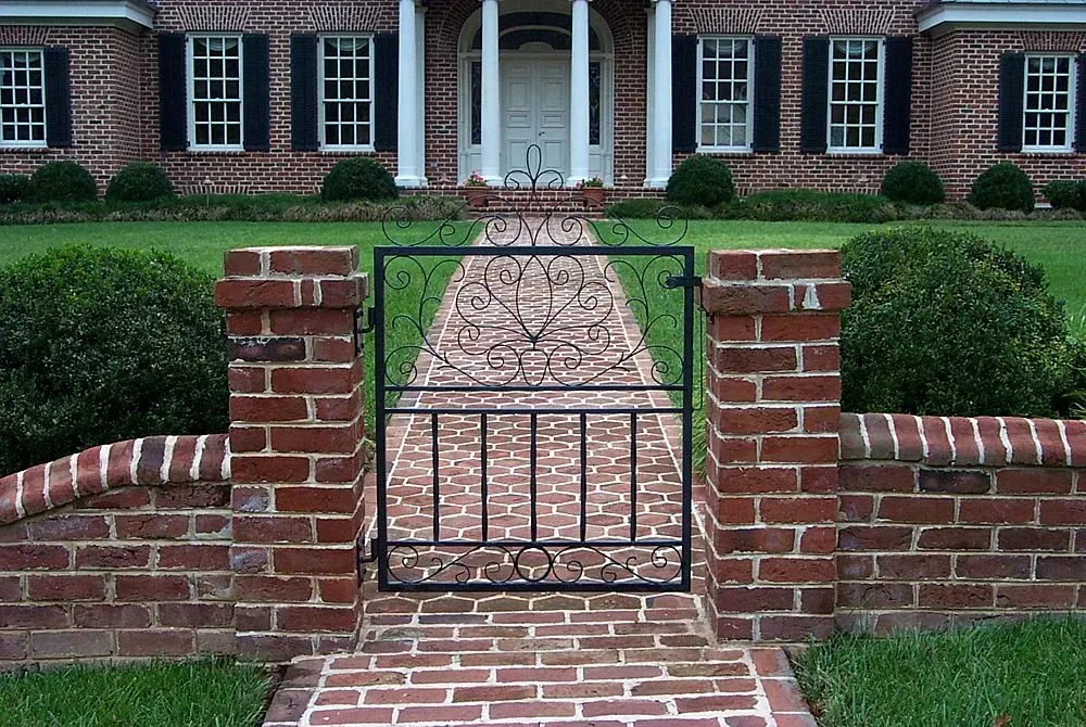 Brick house with a wrought iron gate leading to the front door.