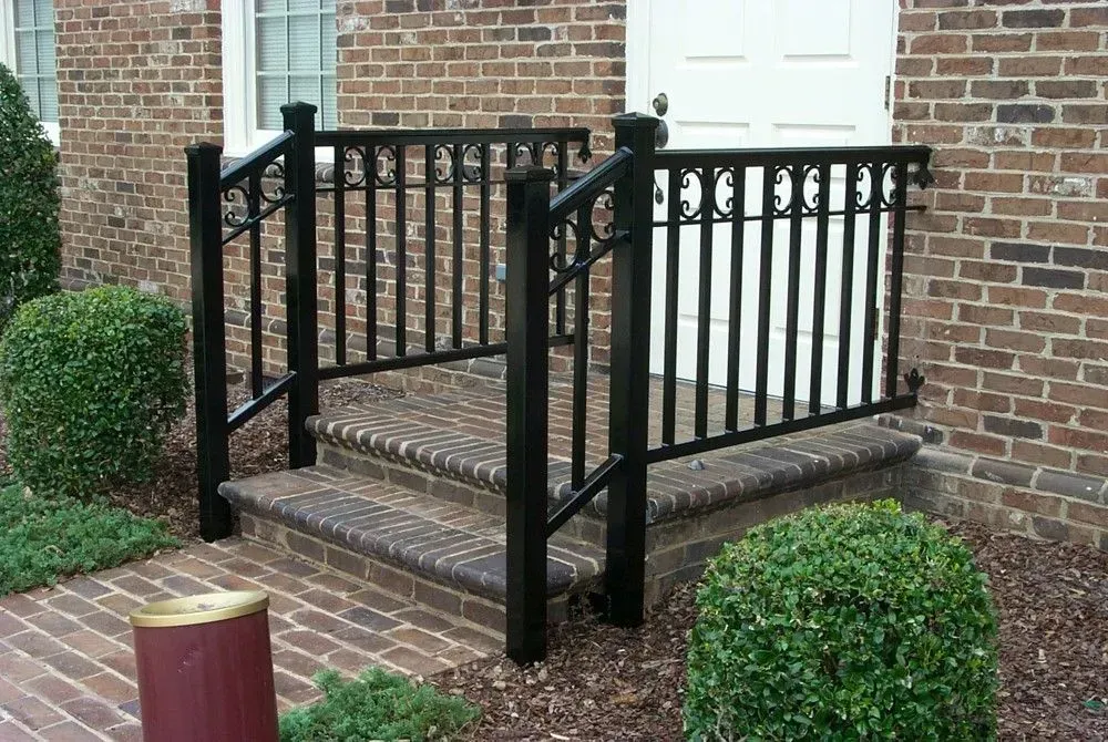 Black iron handrails on brick steps leading to a white door.