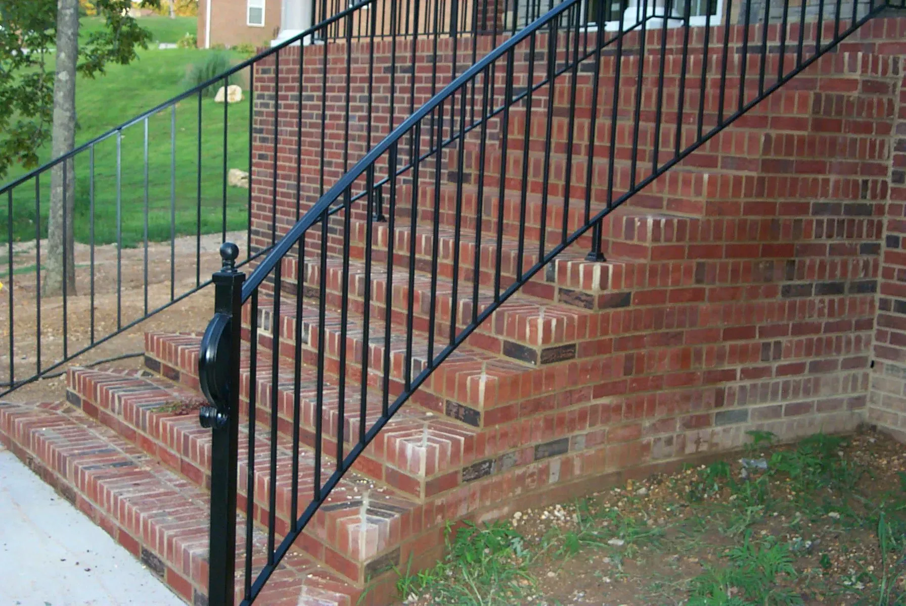 Brick steps with black metal railing leading up to a building entrance.