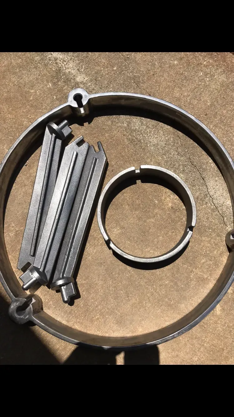 Metal parts laid out on a rough surface; includes rings and rectangular pieces.