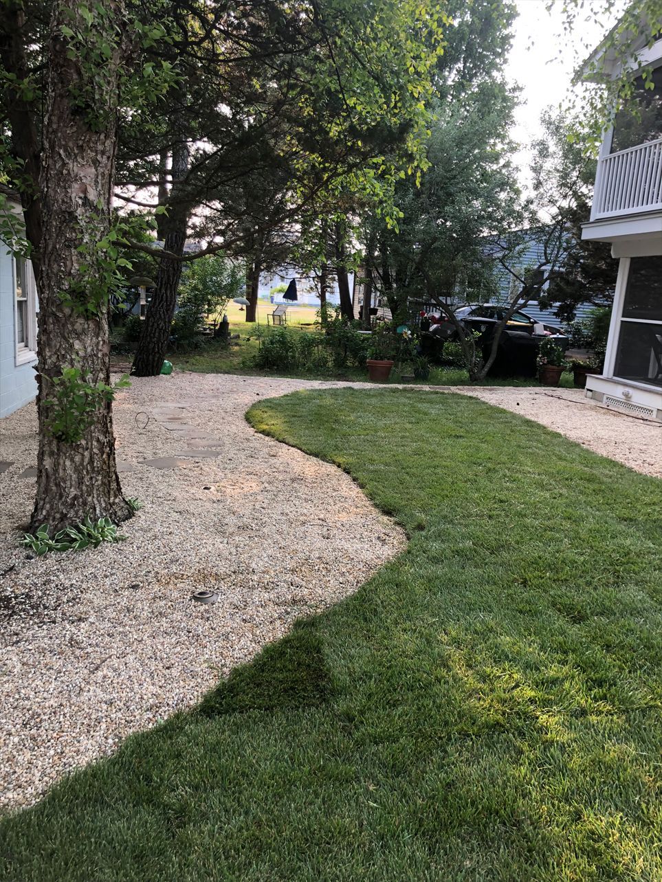 A lush green lawn with a gravel path leading to a house.