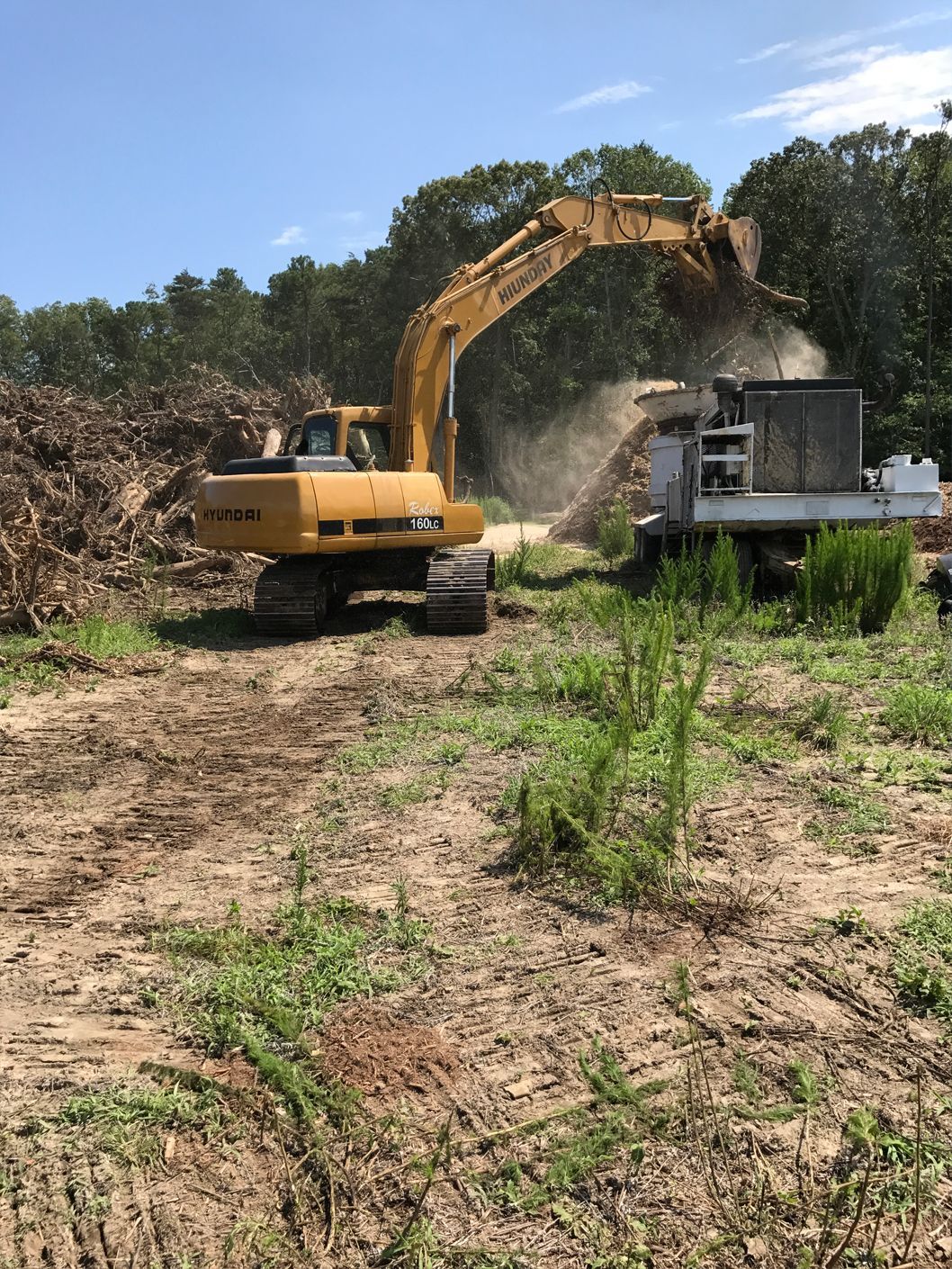 A yellow excavator is moving dirt in a field.