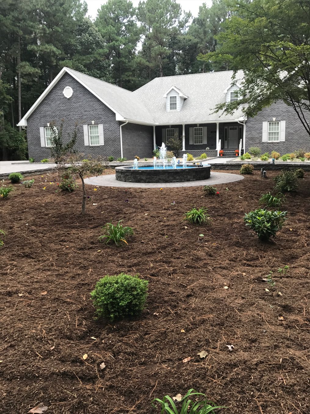 A large brick house with a fountain in front of it.