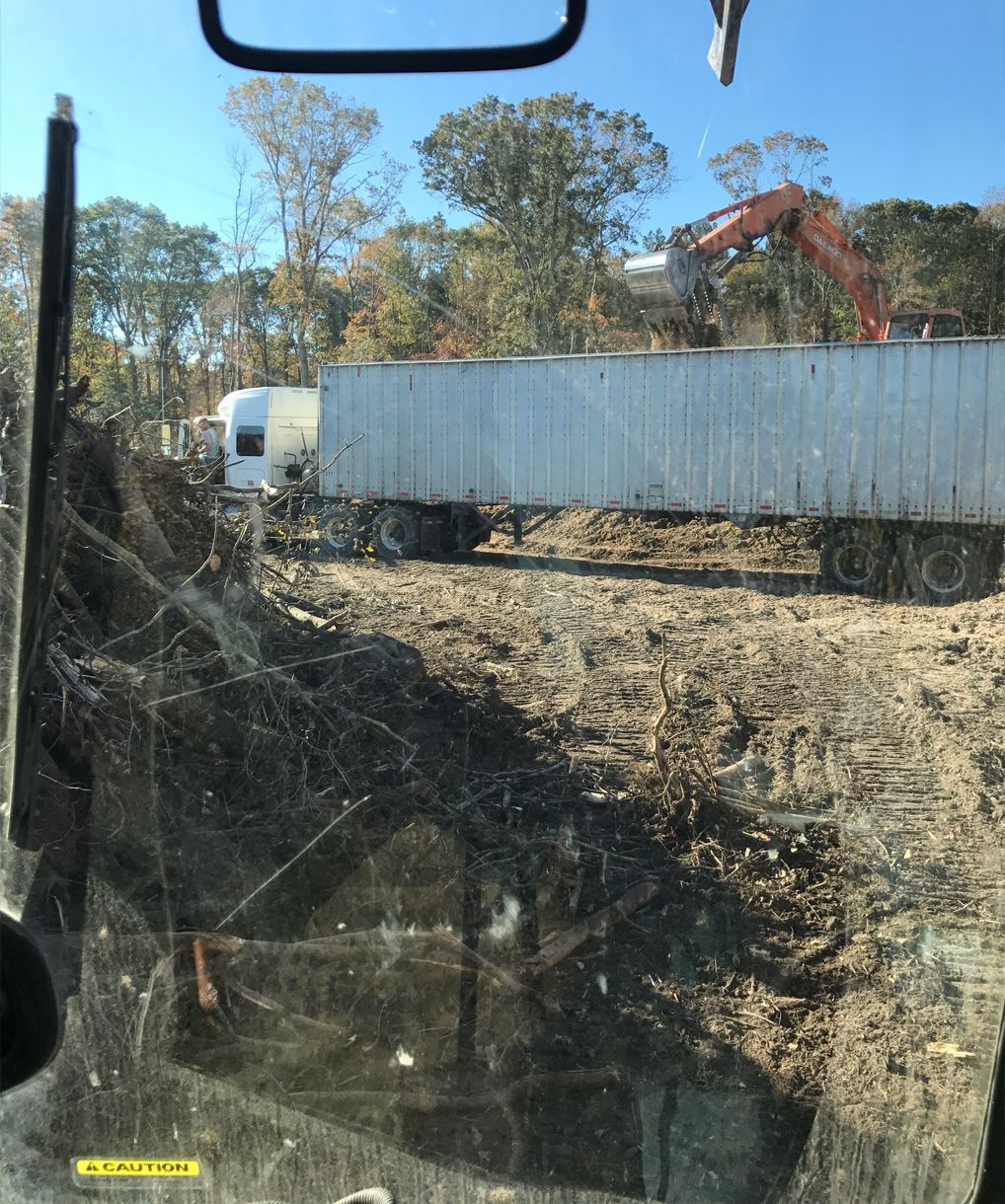 A white semi truck is parked in a dirt field