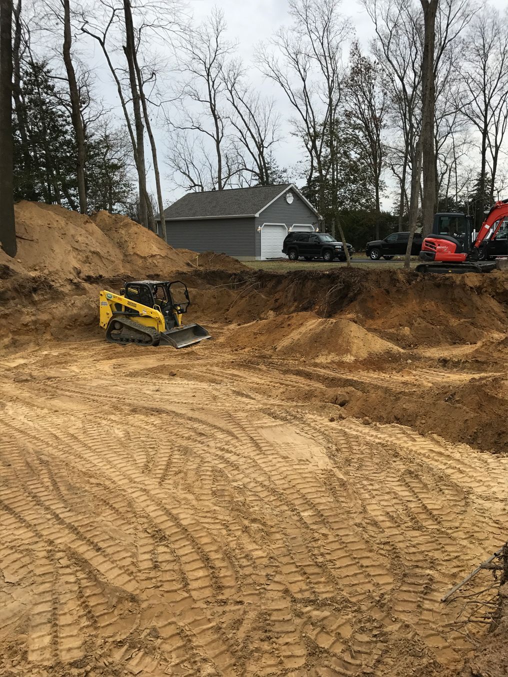 A bulldozer is digging a hole in the dirt in front of a house.
