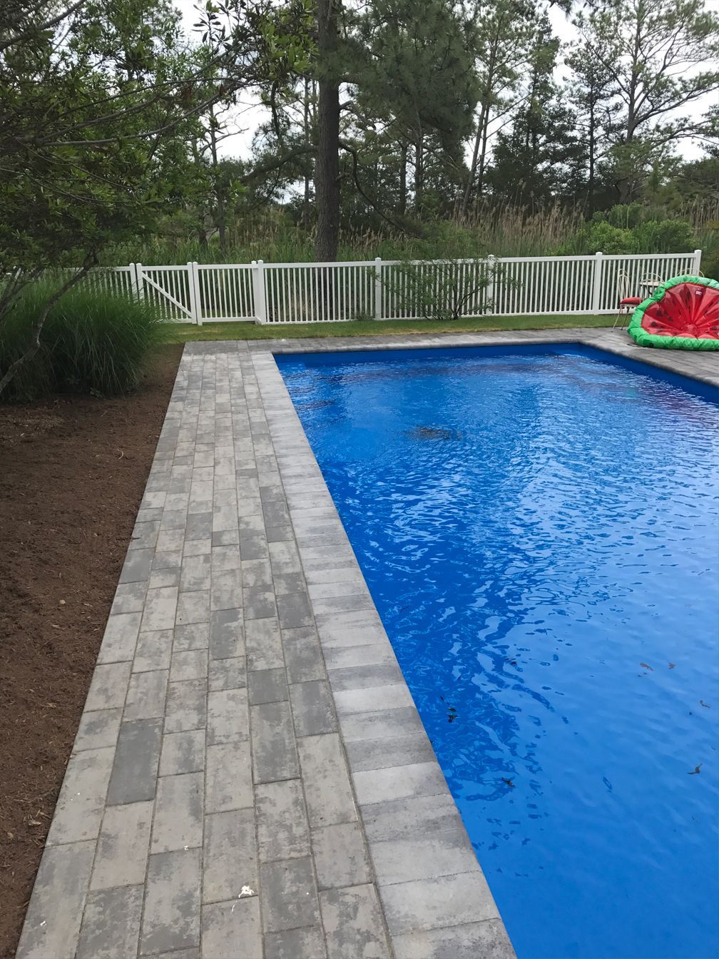 A large swimming pool with a watermelon float in the water.