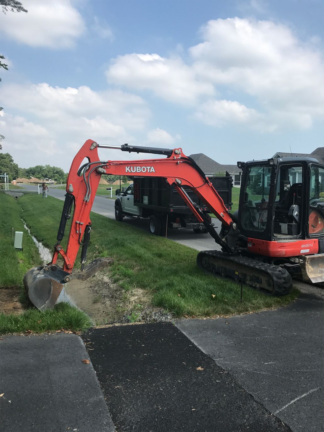 A red and black excavator is parked on the side of the road.